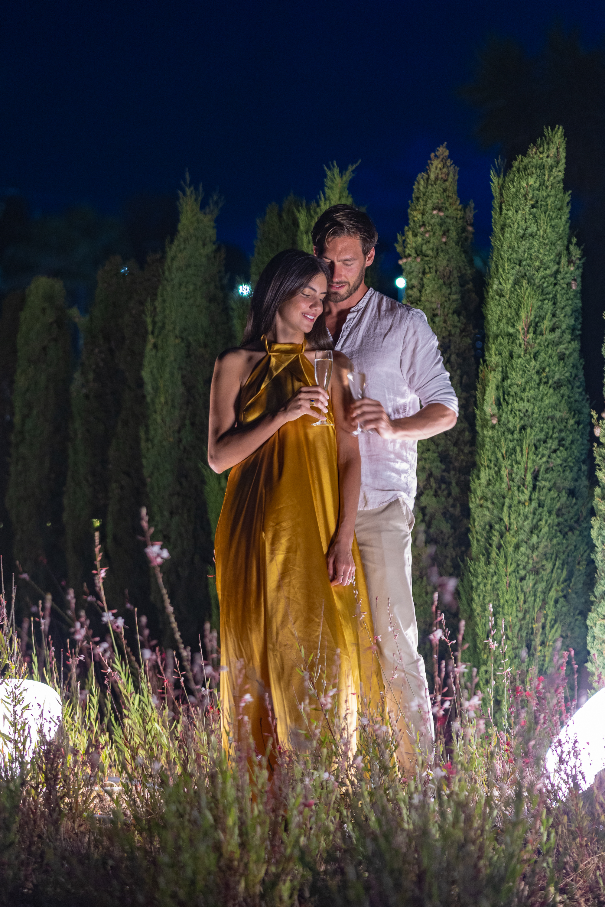 Couple enjoying a drink at night in the gardens of Miraggio Resort