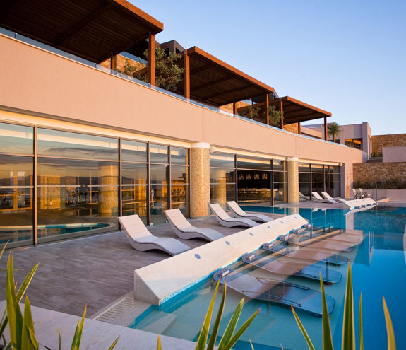 Luxury outdoor spa pool area with sun loungers at sunset