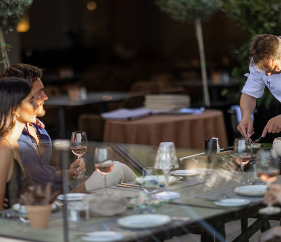 Chef preparing a gourmet dish tableside for guests at Sommelier's 8 restaurant terrace