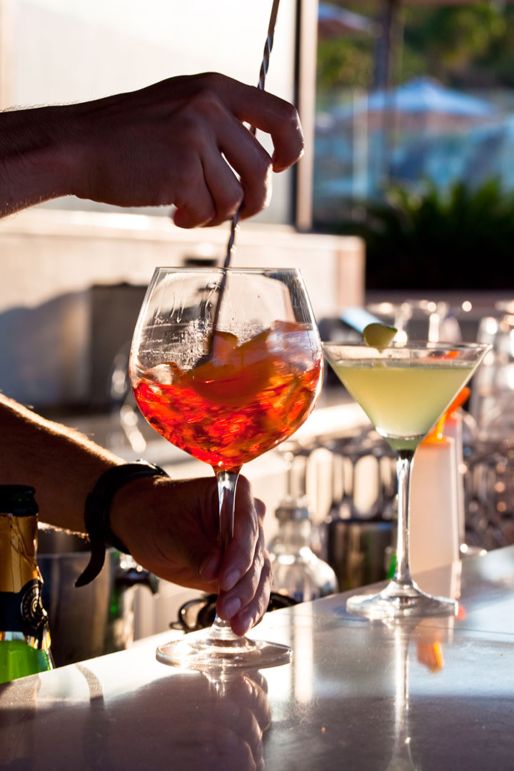 Close up of bartender mixing colorful cocktails behind the counter of Oasis Beach Bar