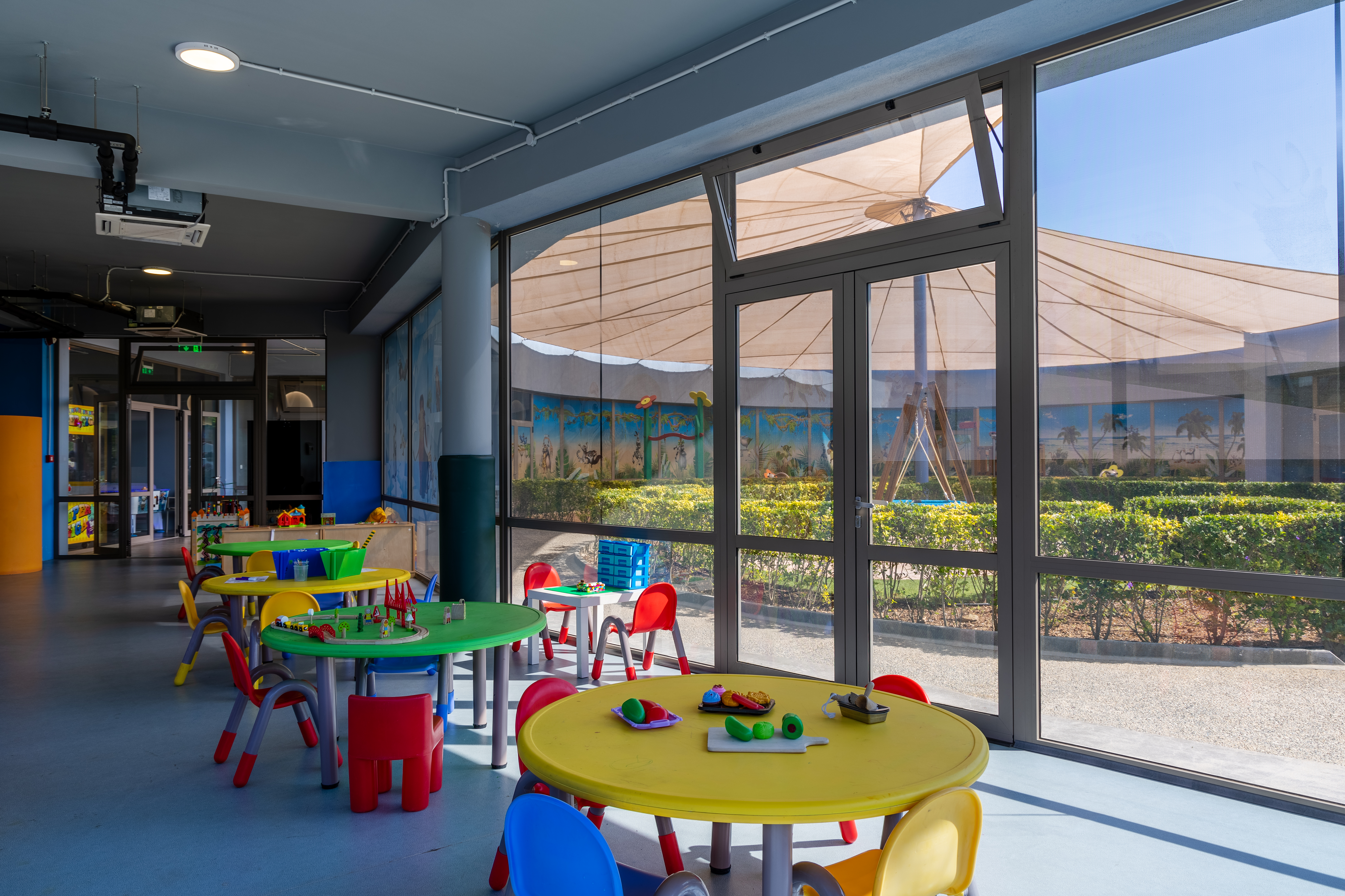 Colorful indoor playroom with tables and creative activities at Kids Planet