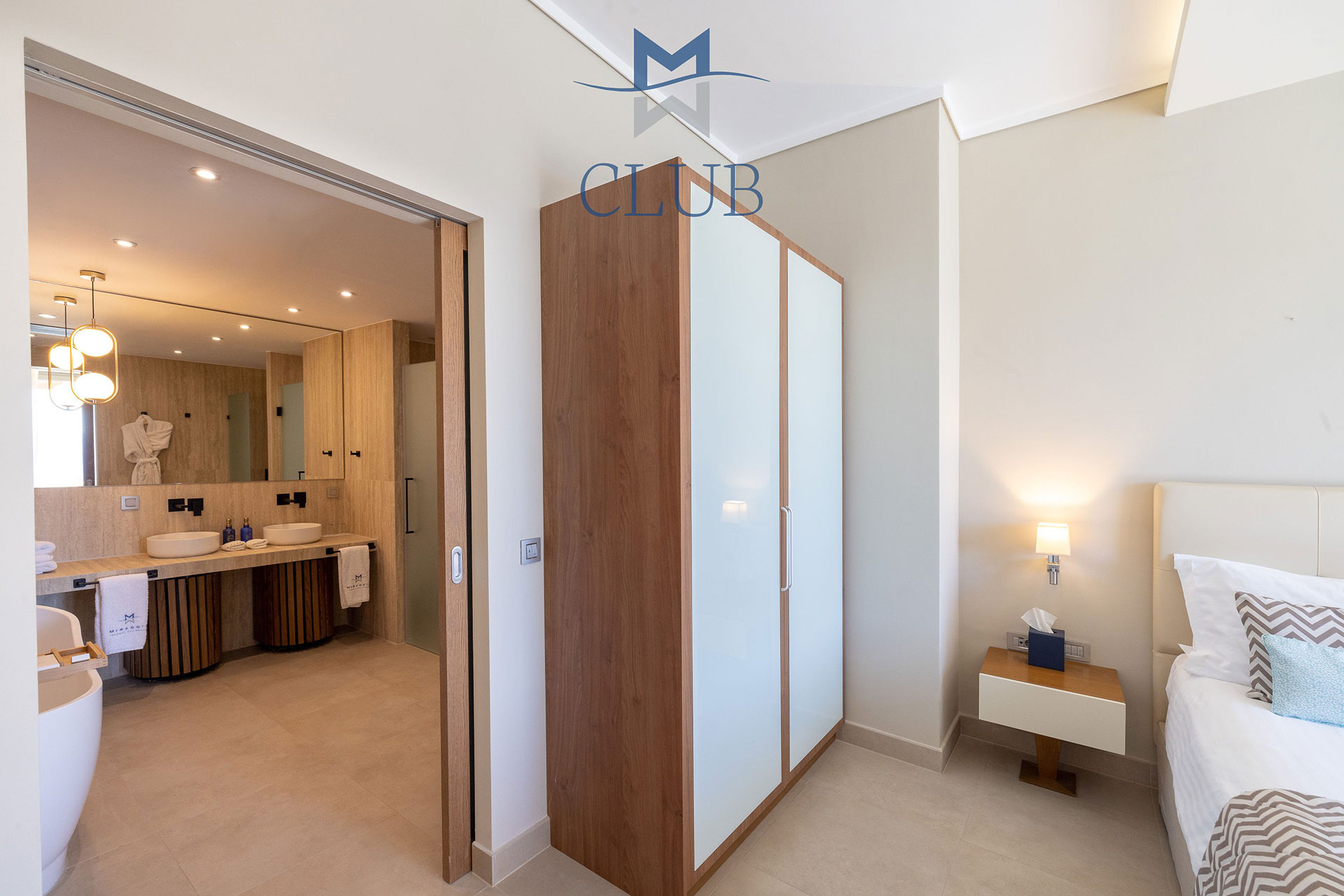 Wide view of suite's bedroom and bathroom with natural lighting