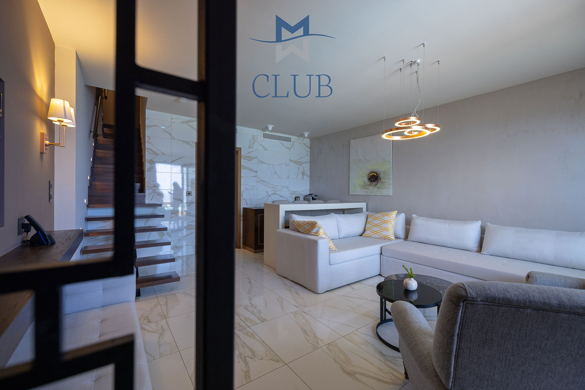 Duplex suite's living room with corner sofa, modern design and floating staircase