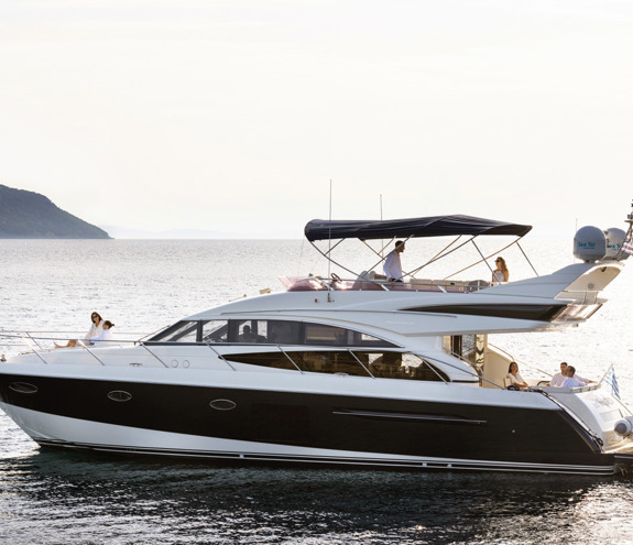 Luxury yacht cruising at sunset with guests relaxing on multiple decks over calm sea