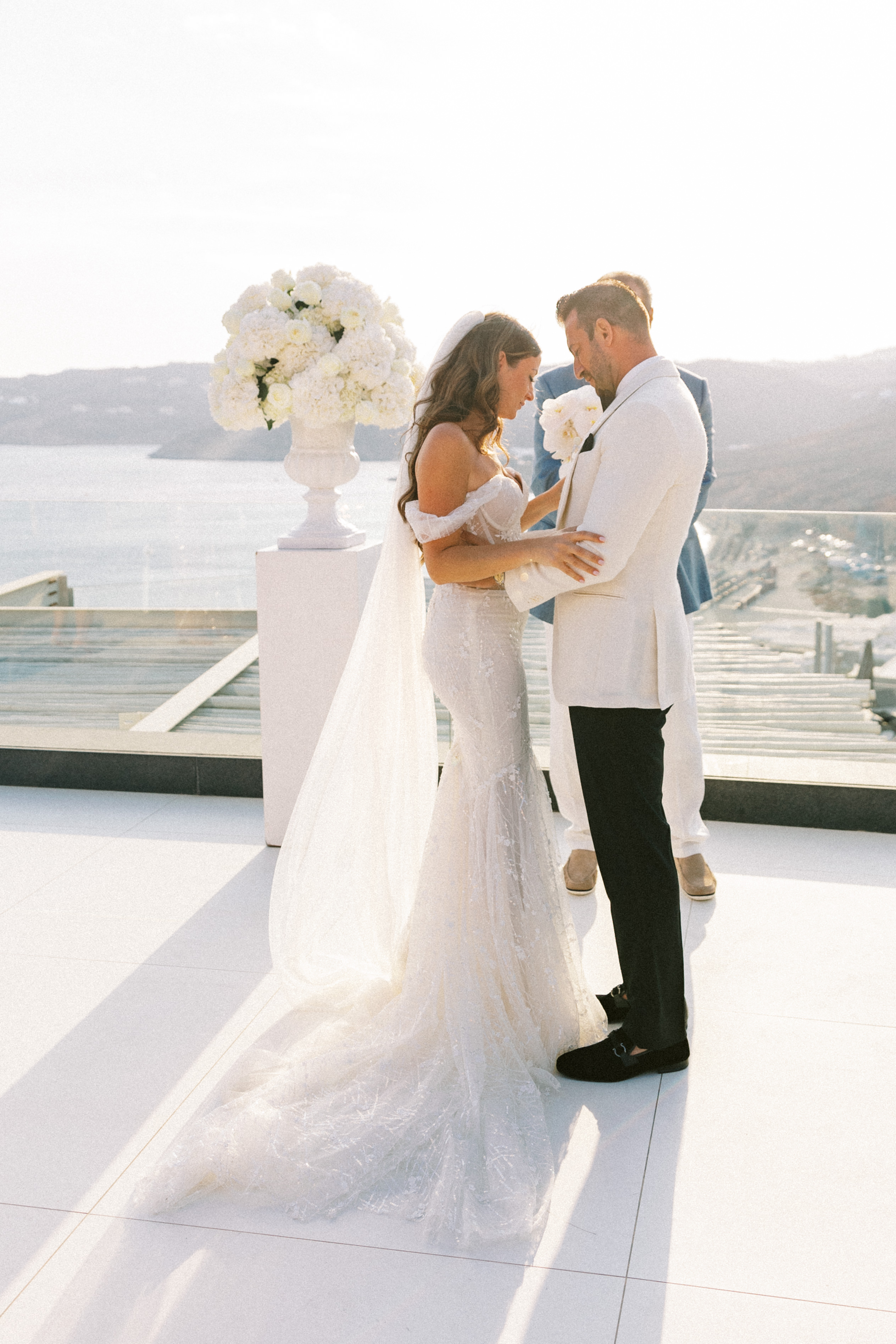 Bride and groom embracing in front of vase decorated with white roses and flowers