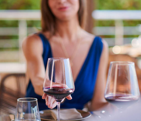 Two glasses of red wine and a woman in the background