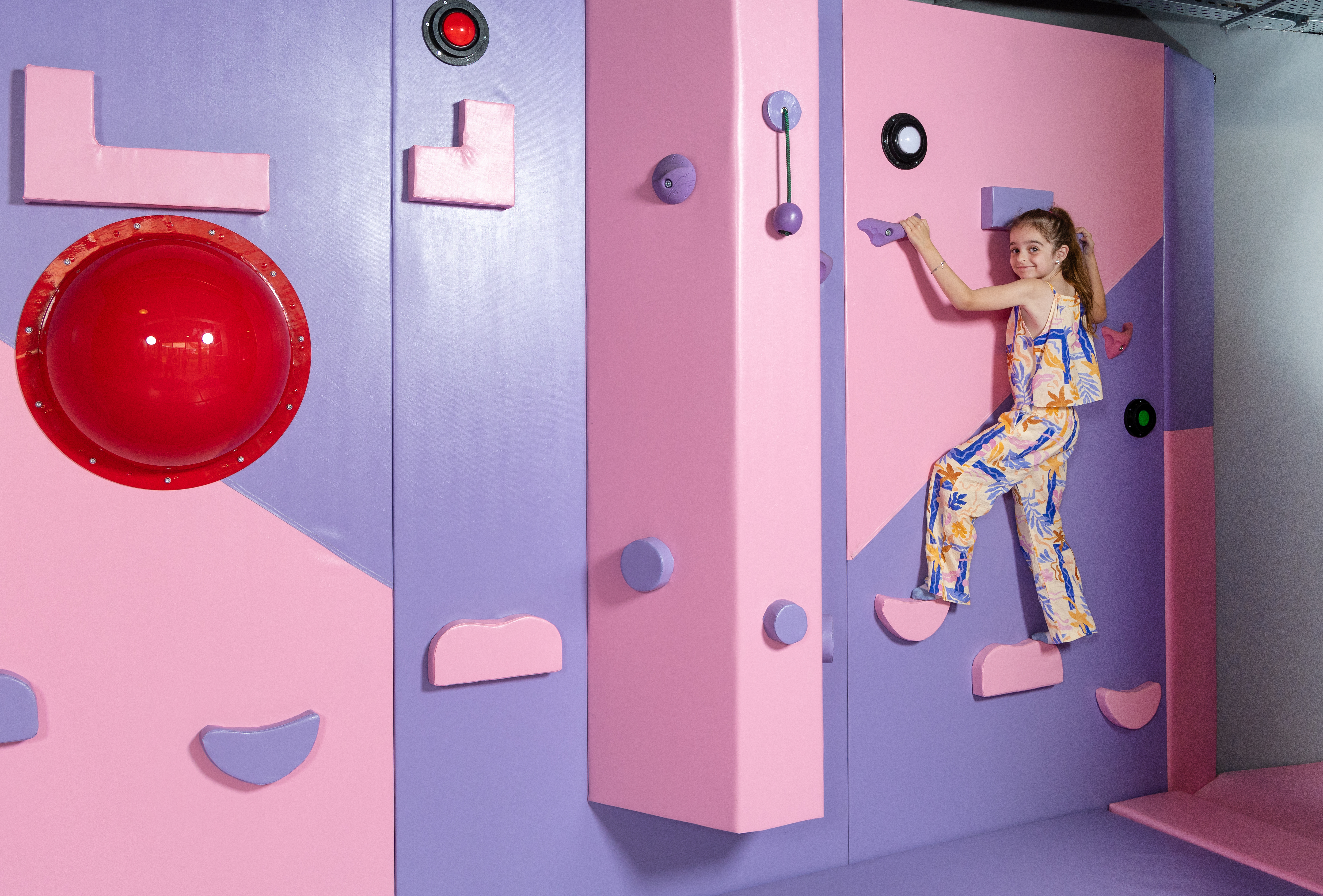 Smiling girl climbing the colorful soft wall at the Kids Planet indoor play zone