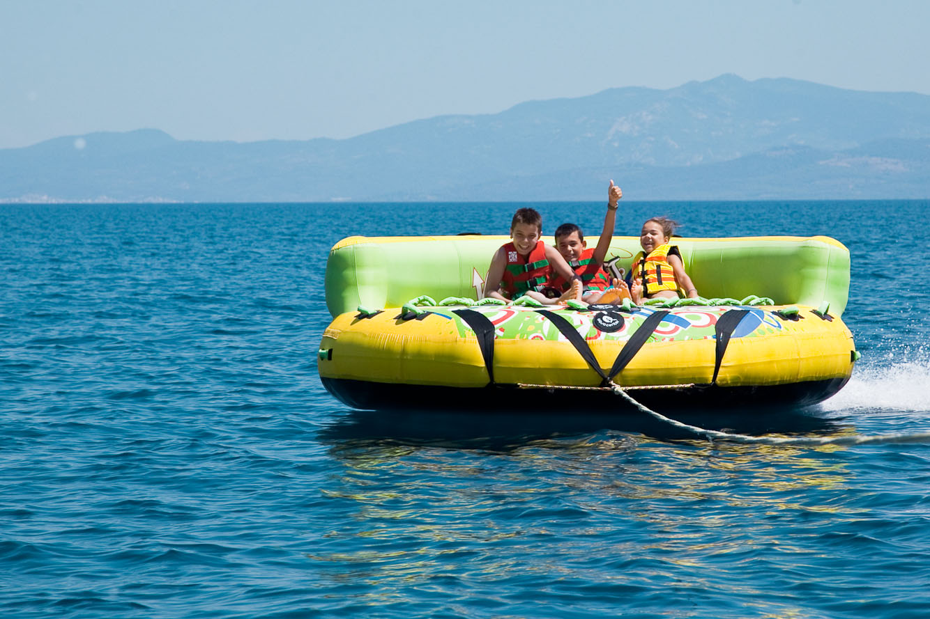 Children enjoying fun inflatable water ride on the sea during sunny day