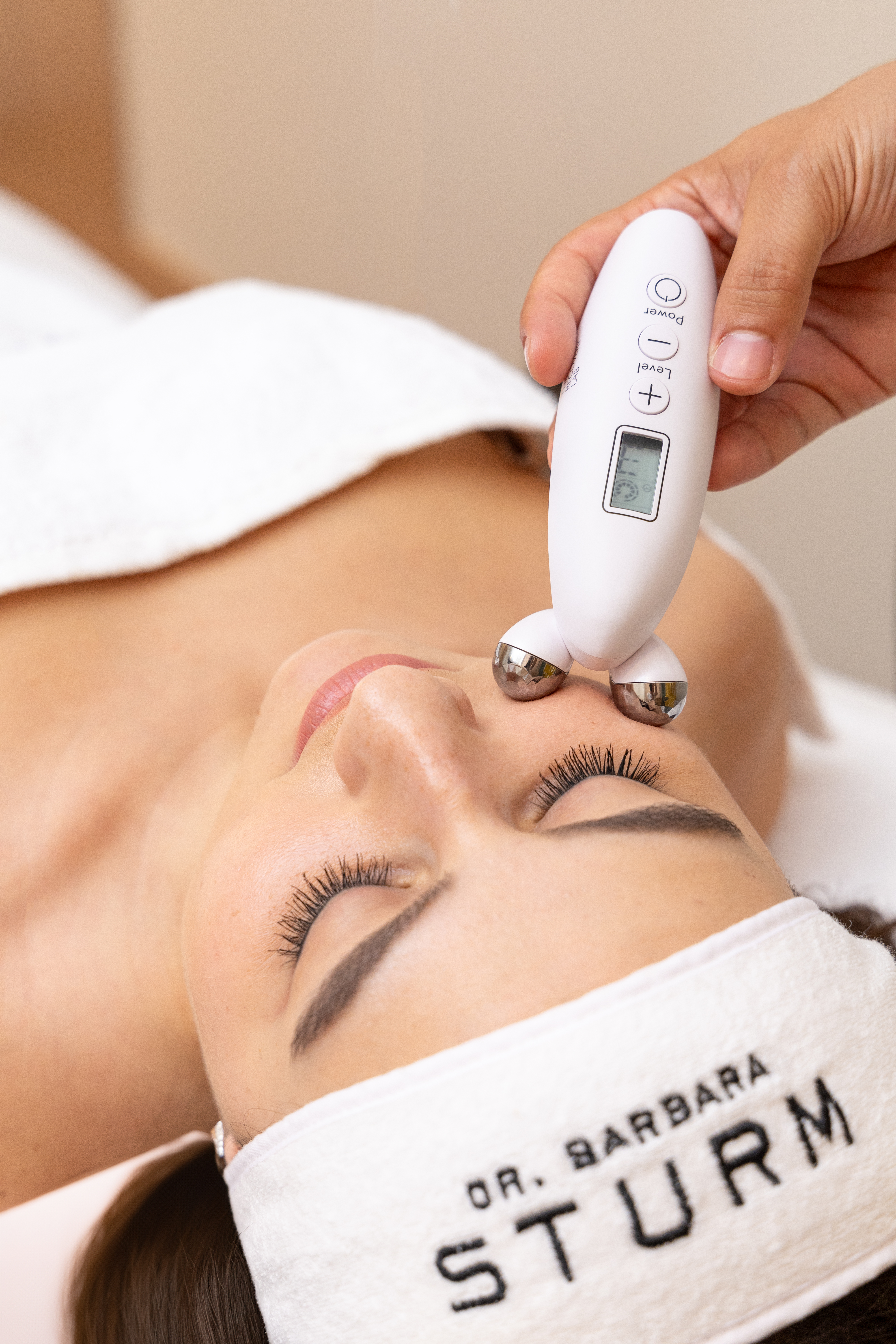 Therapist using a facial massage tool on a woman's face in a treatment room