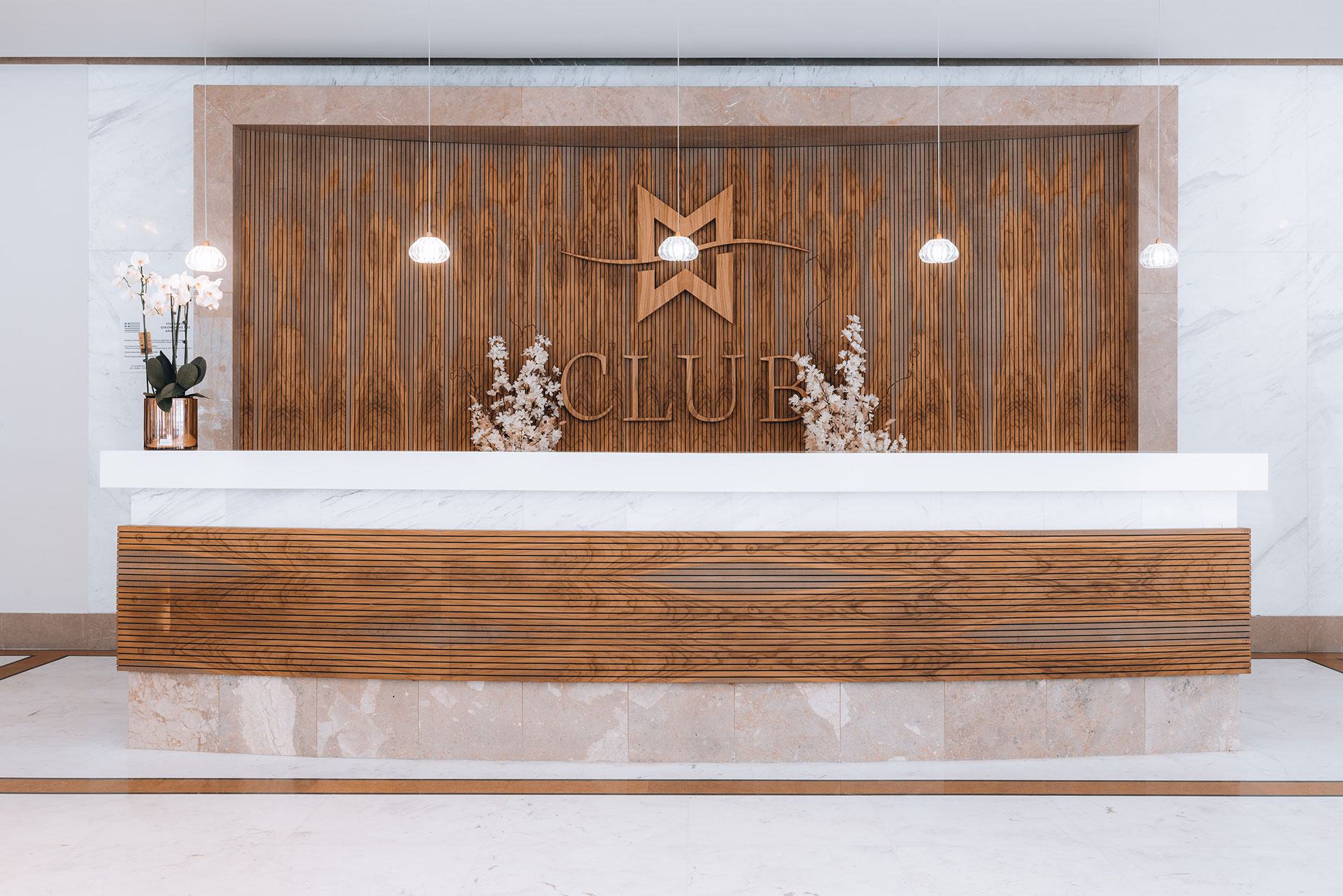 Elegant wooden reception desk with modern lighting and floral decor at Club area