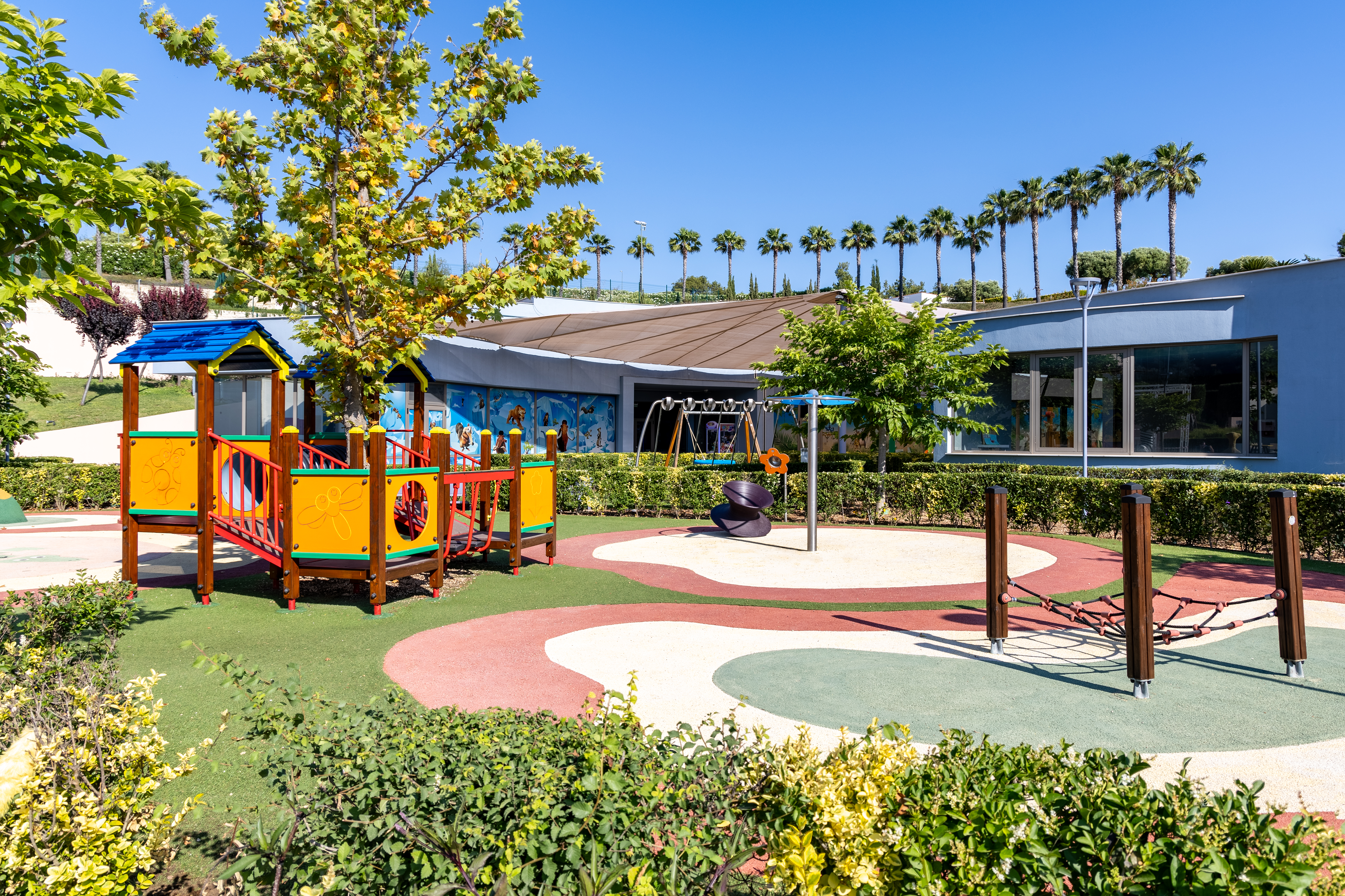 Colorful outdoor playground surrounded by greenery at Kids Planet