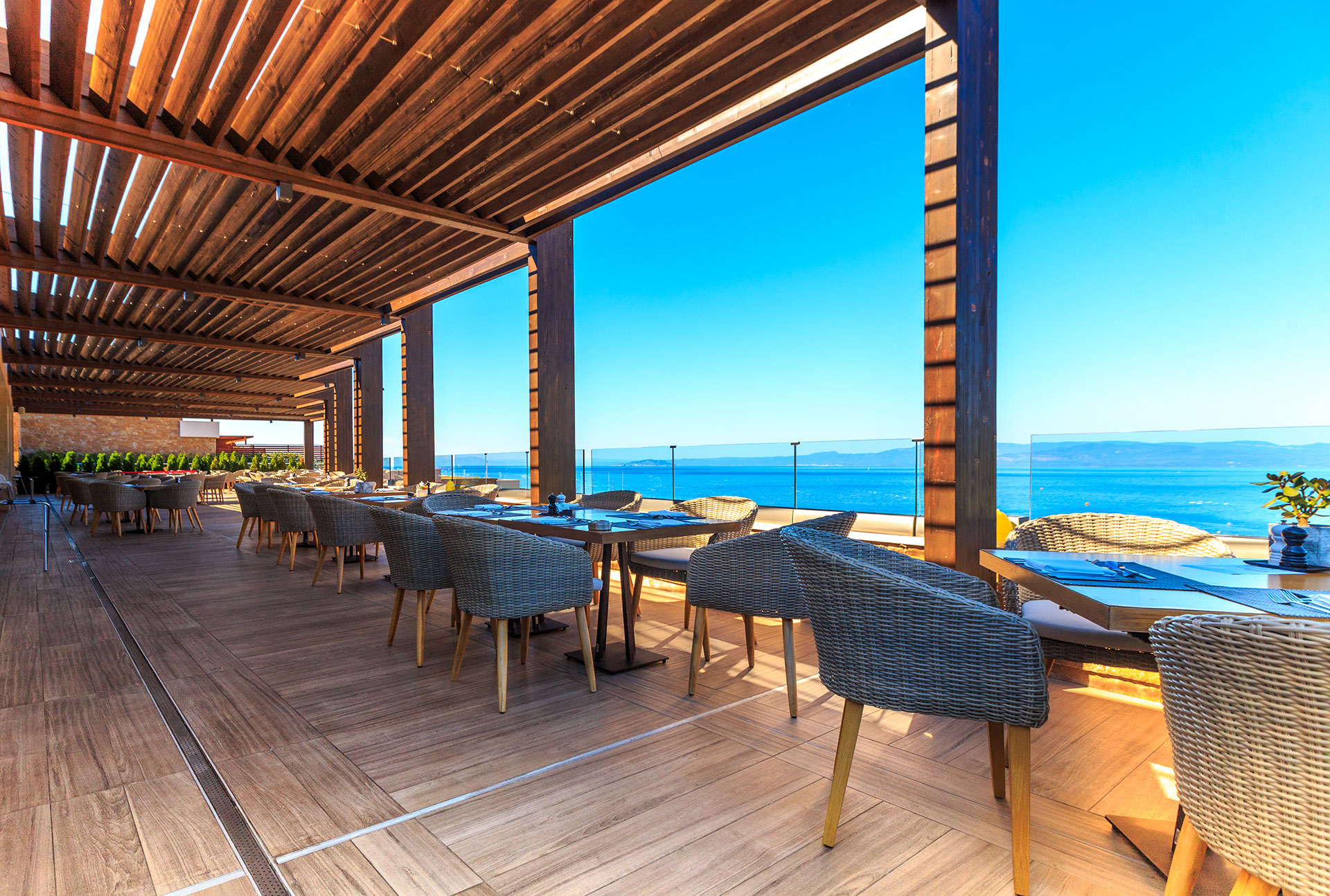 Outdoor dining terrace with wooden pergola, sea view, and elegant seating at Kritamo restaurant
