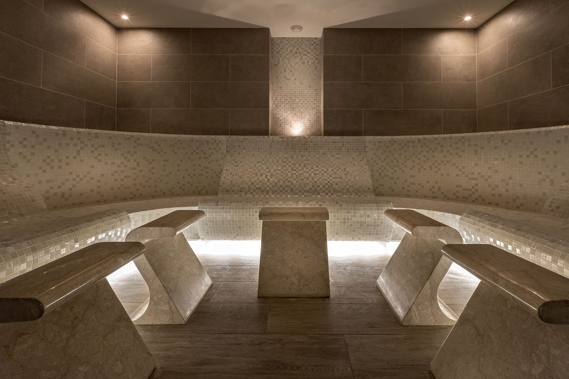 Elegant tiled steam room with warm lighting and marble seating
