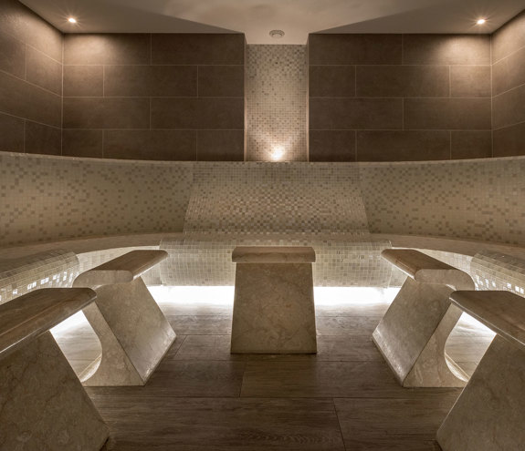 Elegant tiled steam room with warm lighting and marble seating