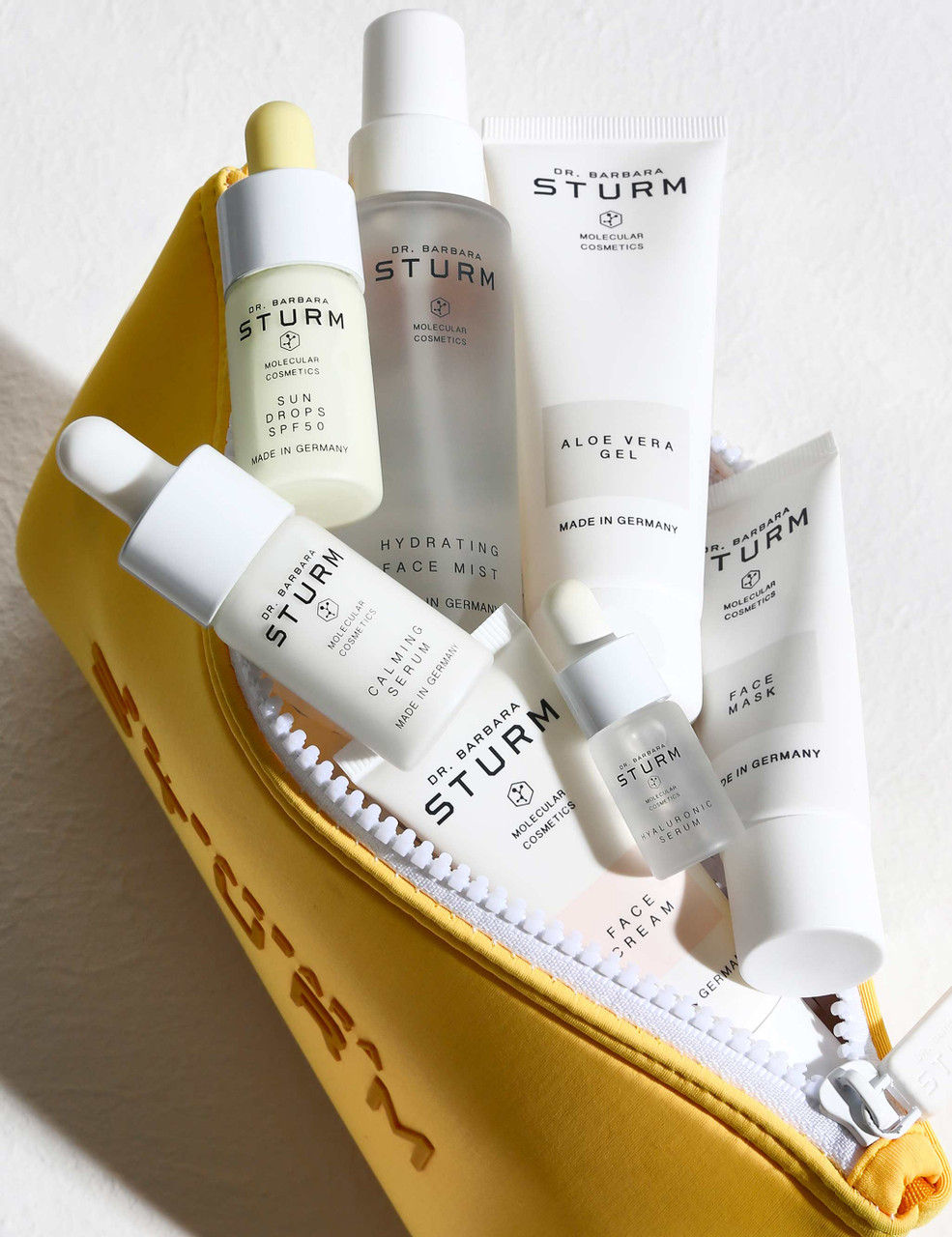 Dr. Barbara Sturm summer skincare essentials in yellow cosmetic bag