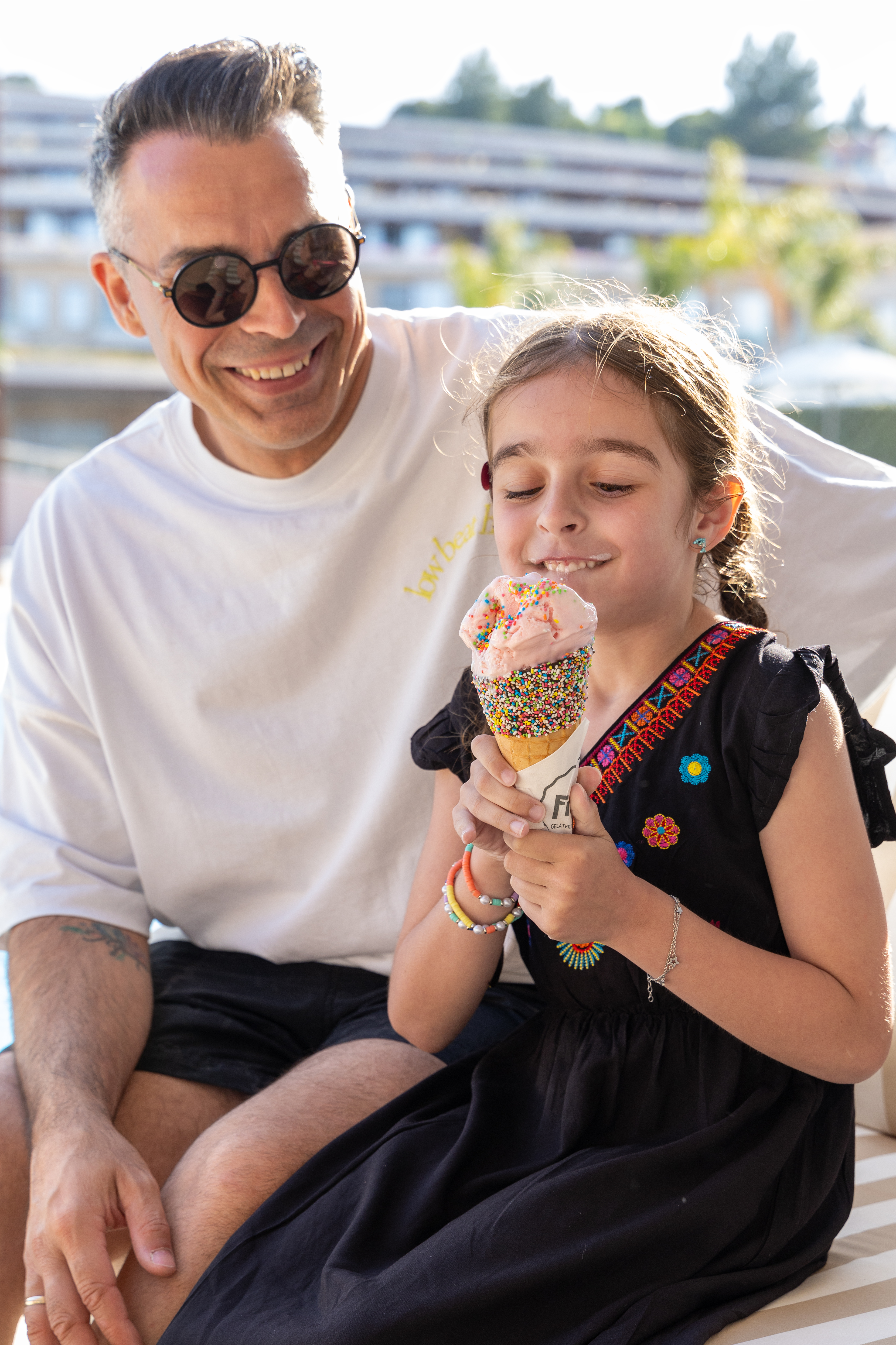 Father and daughter enjoying fregio ice cream cone with sprinkles on a sunny day