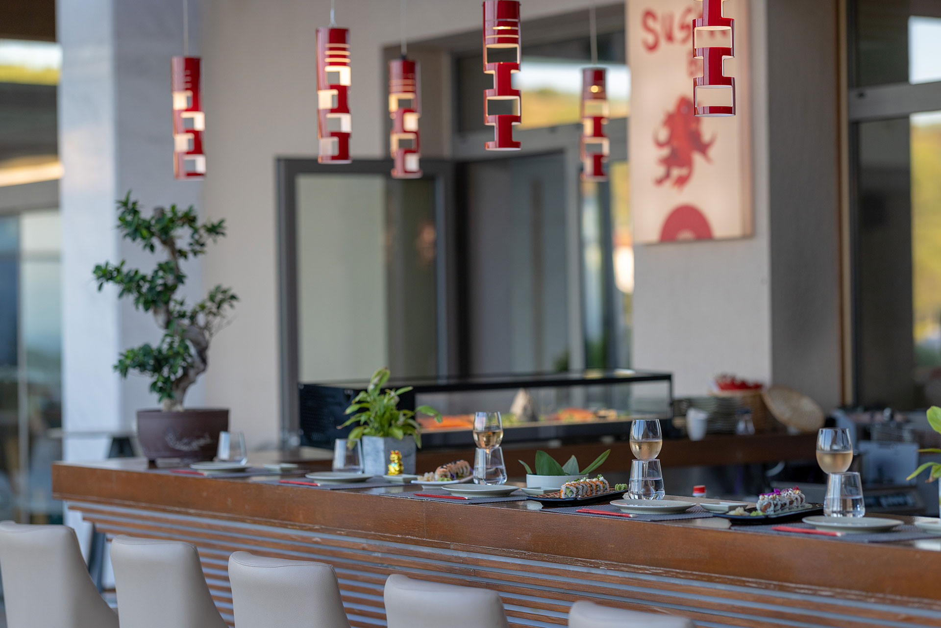 Modern sushi bar with minimalist decor, red pendant lights, and white wine pairings