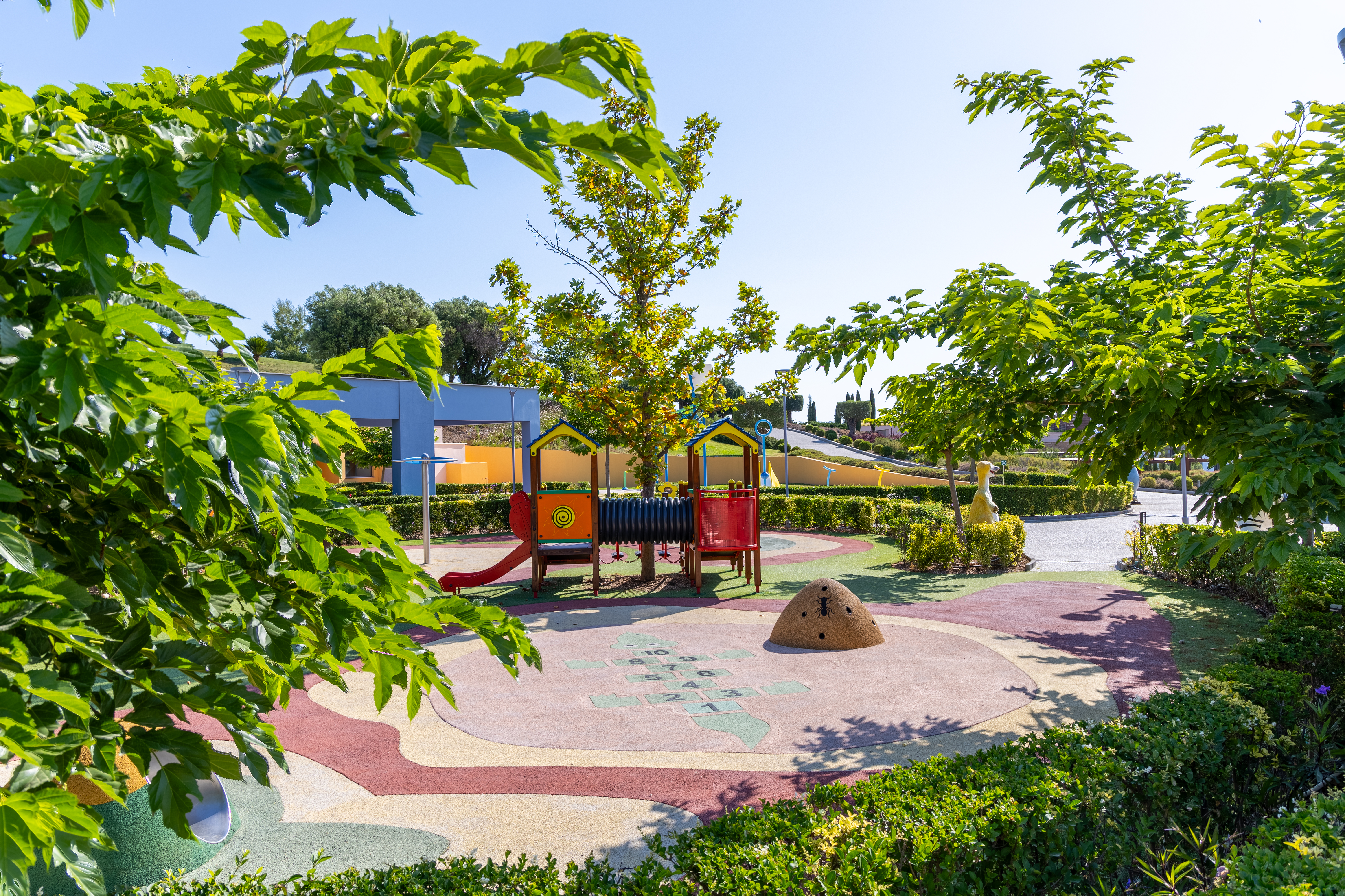 Colorful outdoor playground surrounded by lush greenery and trees