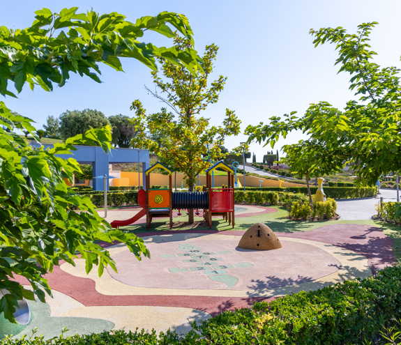 Colorful outdoor playground surrounded by lush greenery and trees