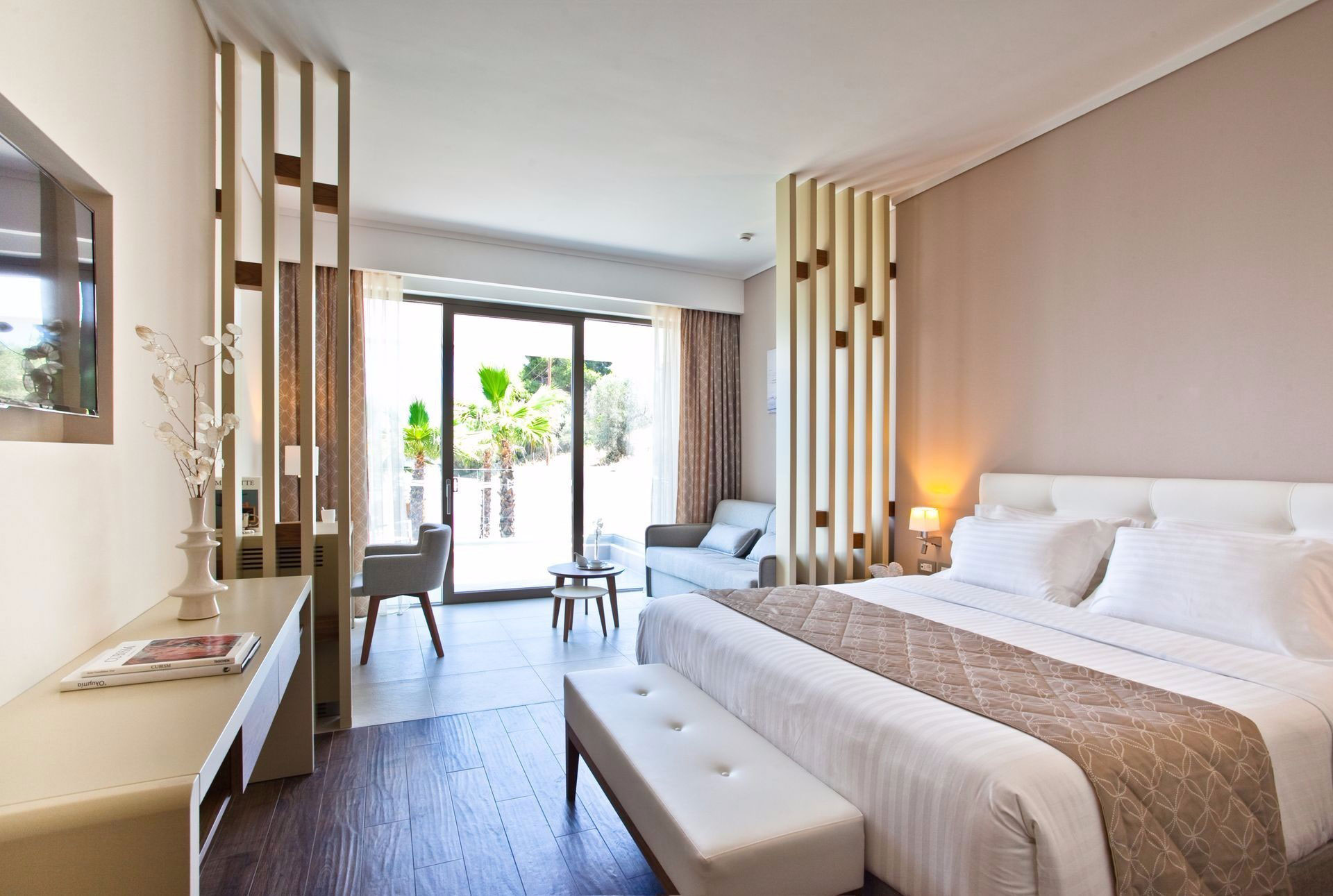 Bright family room with elegant decor, soft beige tones, and terrace overlooking palm trees