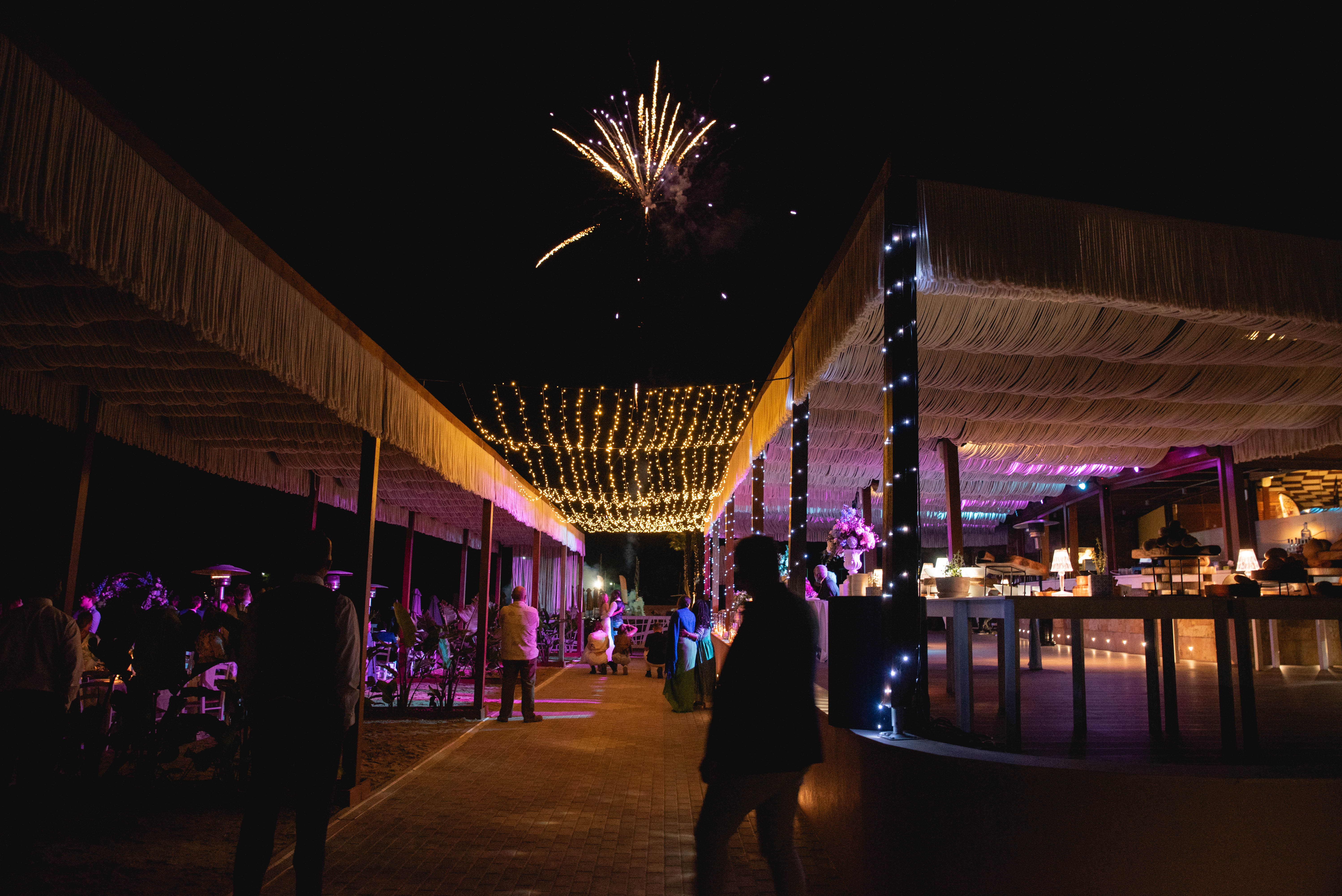 Night firework show for wedding event near the tables with ambient purple lighting