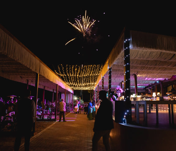 Night firework show for wedding event near the tables with ambient purple lighting