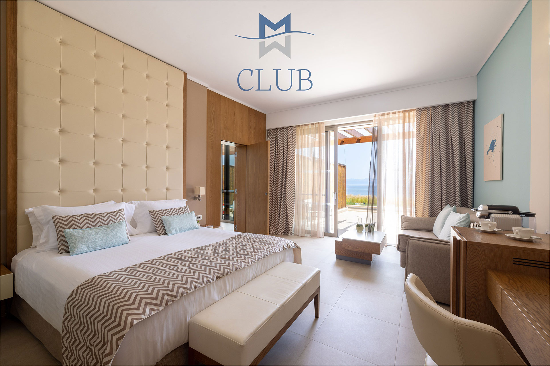 Elegant sea view room with wooden furnishing and details, working desk, seating area and king sized bed