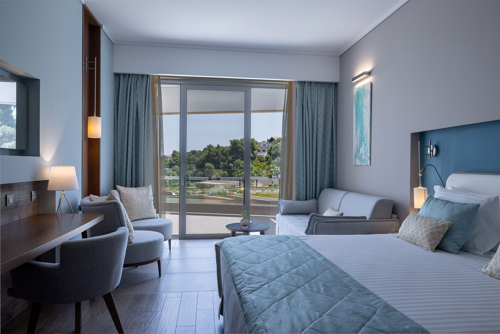 Deluxe room with elegant decor, soft blue tones and private balcony overlooking the gardens and the sea