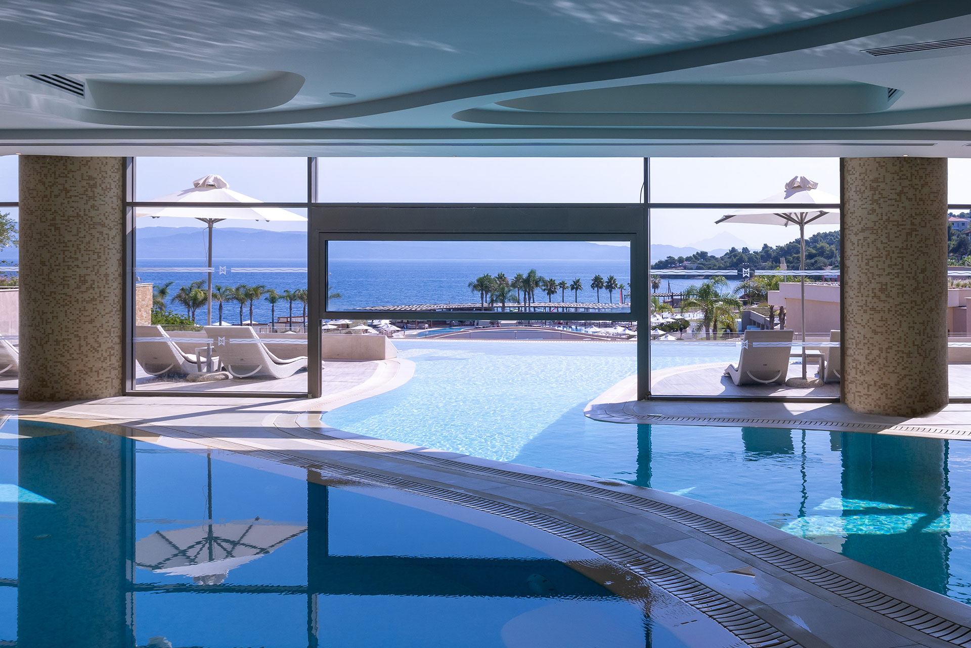 Indoor infinity pool overlooking the sea through large glass windows