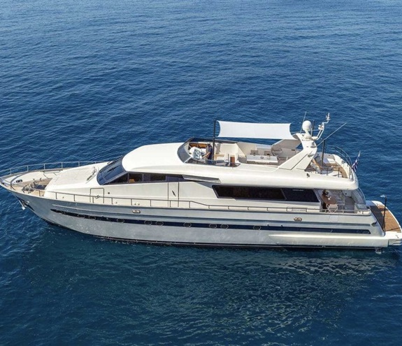 Large white motor yacht cruising on calm blue sea with spacious deck and shaded flybridge