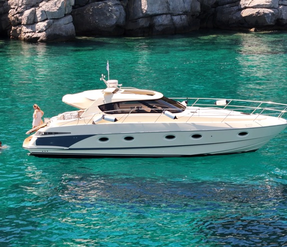 Motor yacht anchored in clear turquoise water with swimmers enjoying the sea nearby