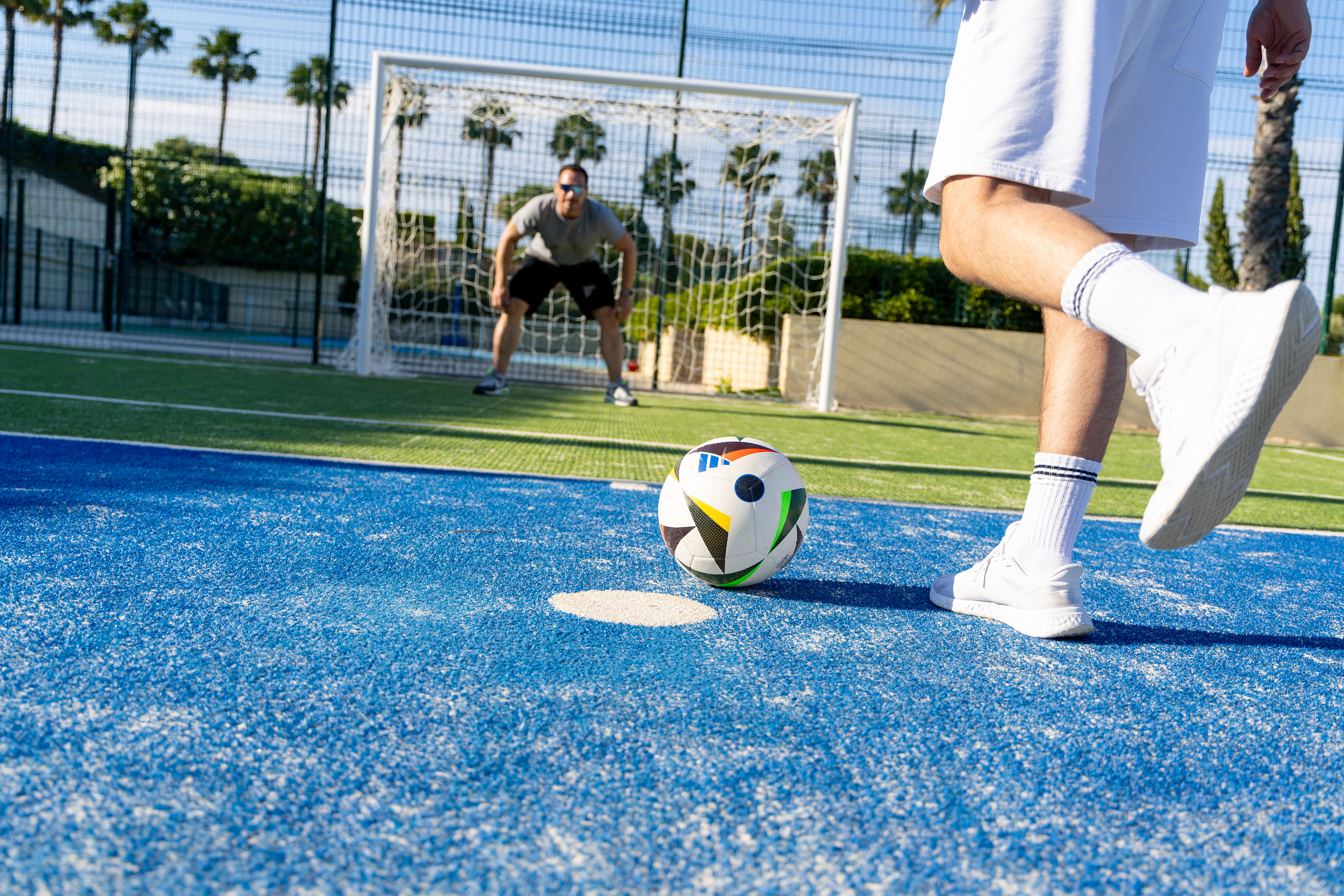 Football player about to shoot towards the goal with the goalkeeper ready to defend