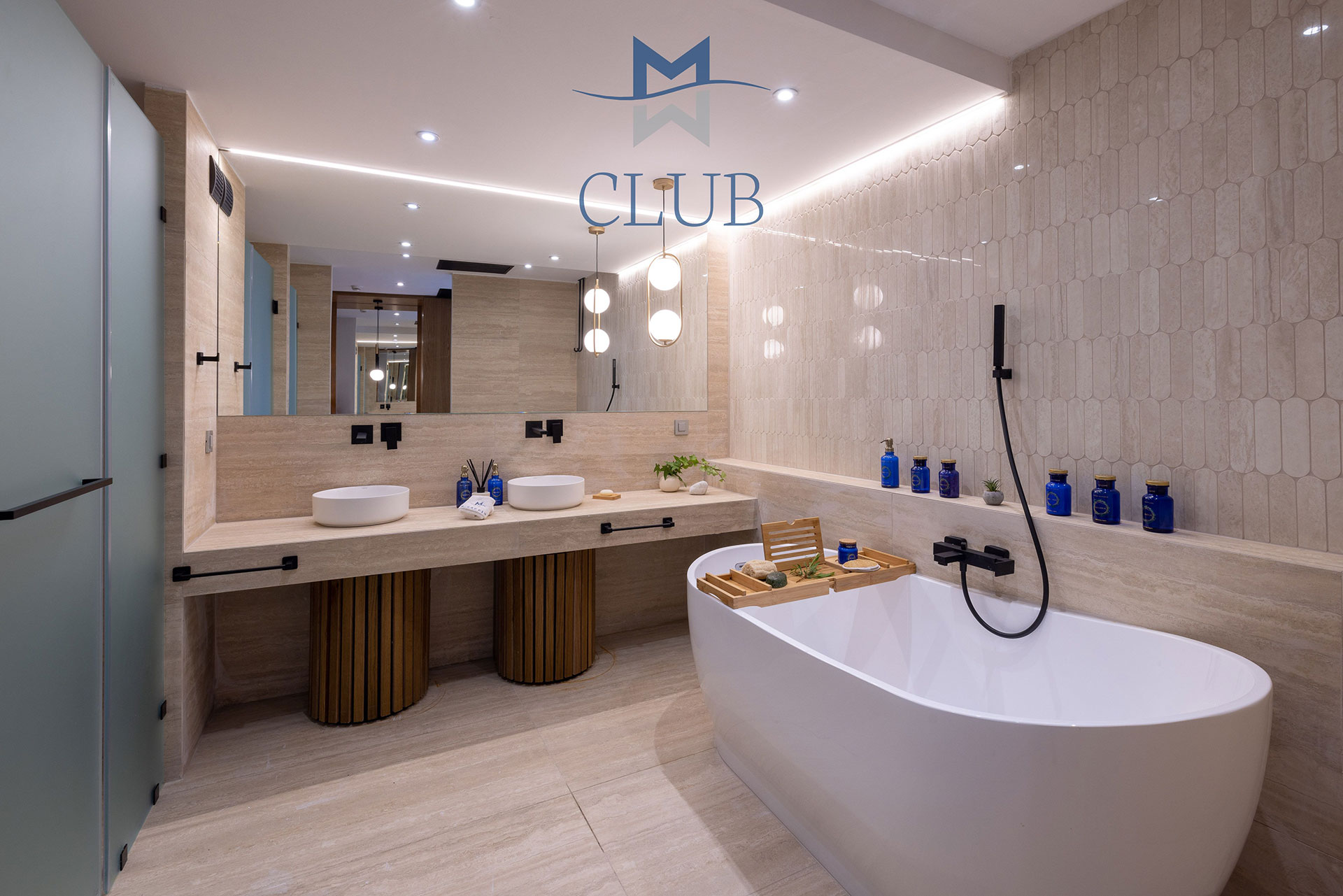 Suite's modern bathroom with frosted glass doors, twin basins, and a freestanding bathtub