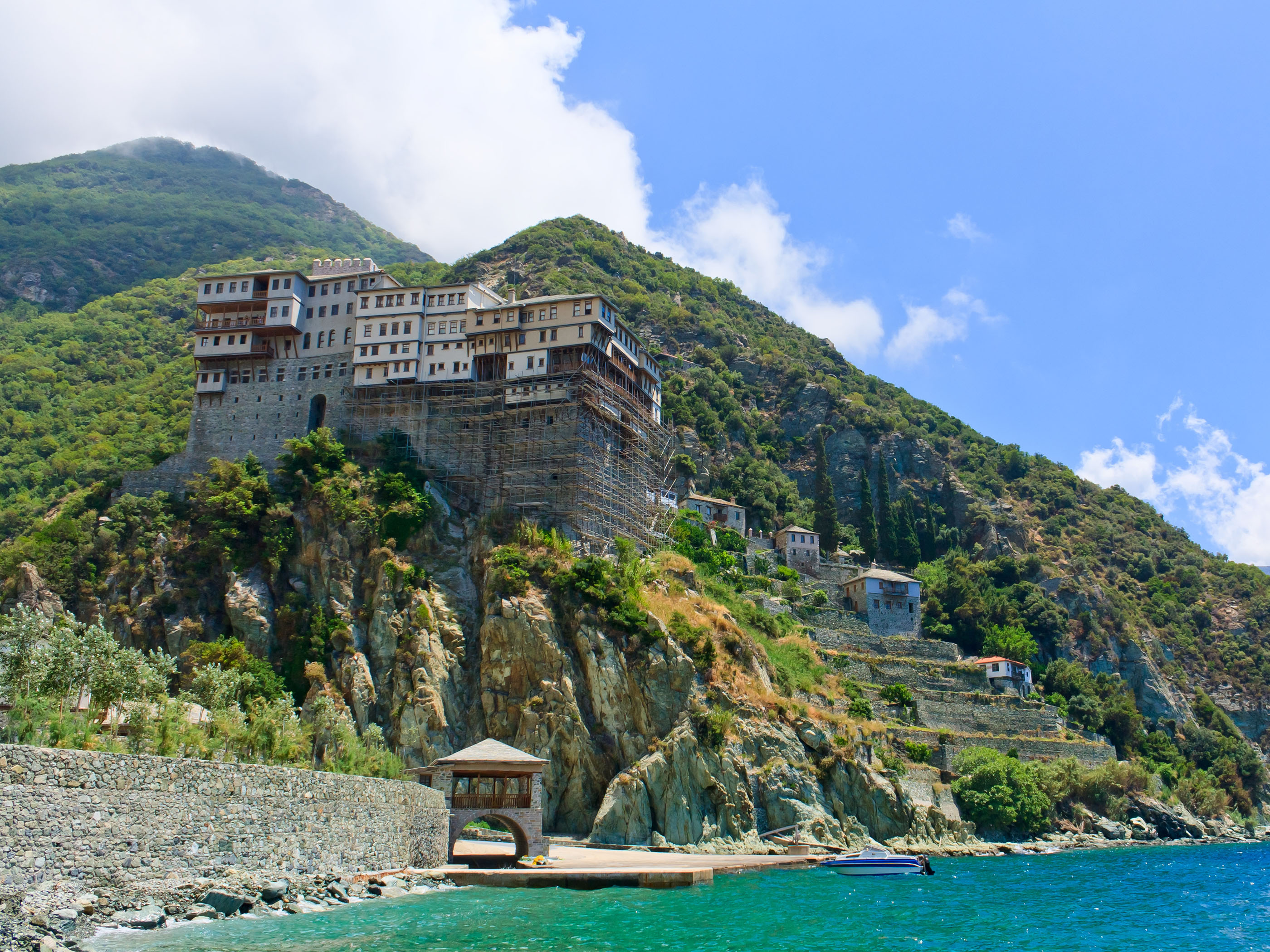 Monastery built on a cliff above the turquoise sea at Mount Athos on a clear summer day