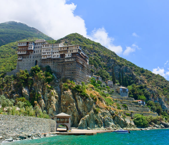 Monastery built on a cliff above the turquoise sea at Mount Athos on a clear summer day