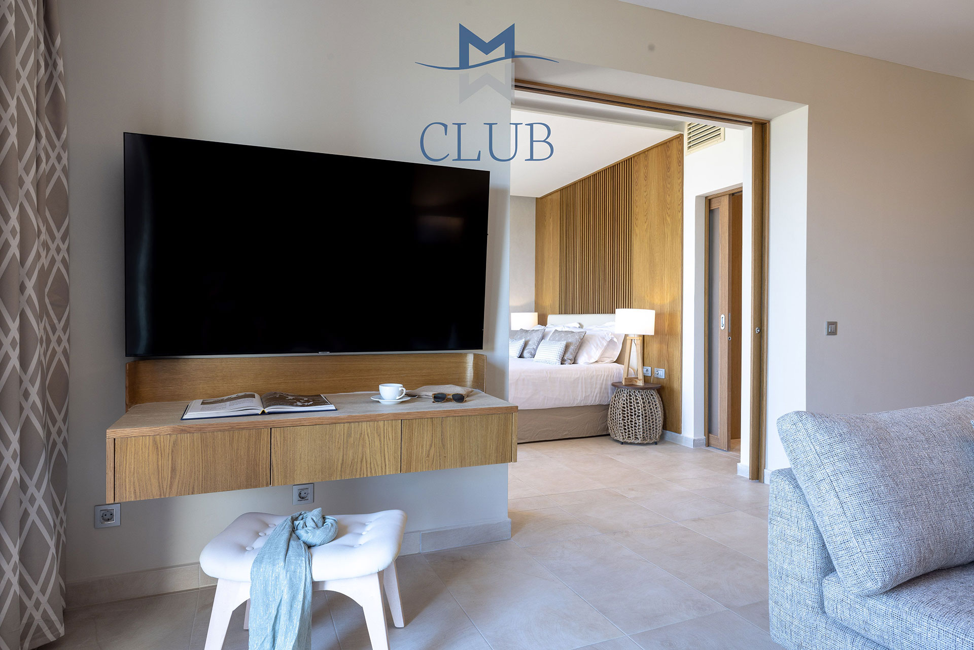 Suite's living area with wall mounted smart TV, sofa and the bedroom in the background