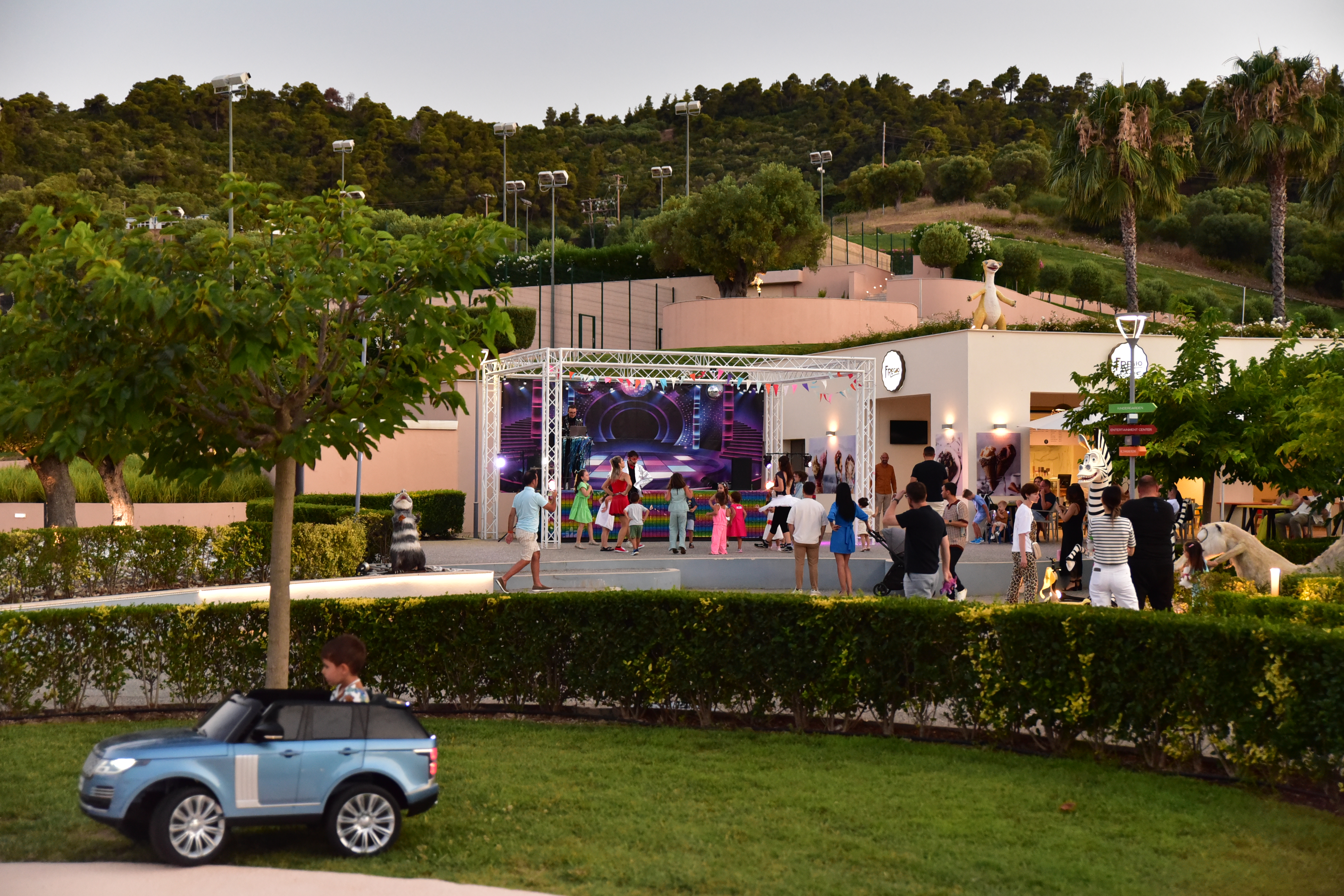 Children and families enjoying an outdoor dance show near Fregio cafe during sunset