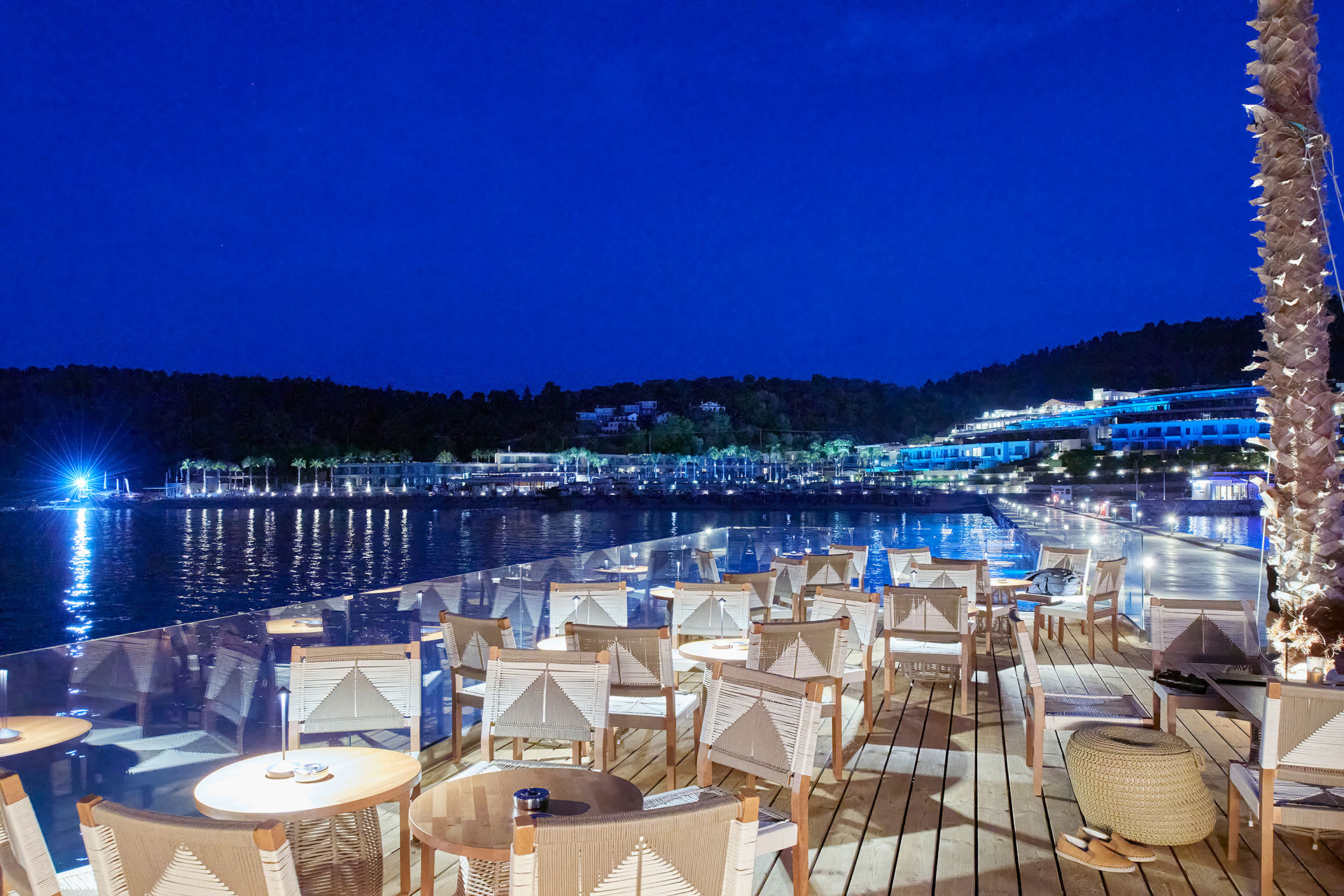 Night view of the illuminated dock with elegant seating and the glowing resort in the background