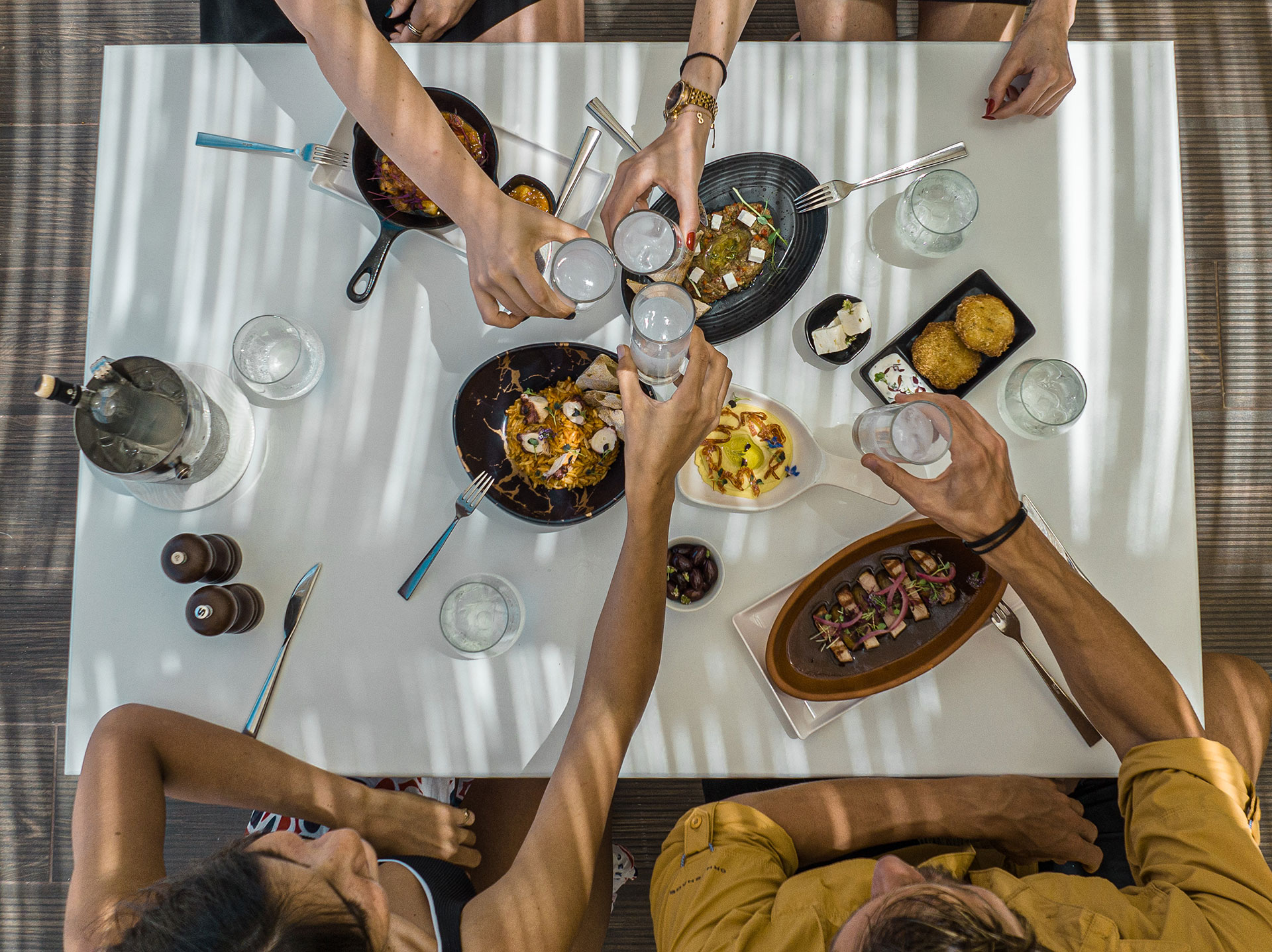 A company enjoying drinking ouzo at Mezedaki beach restaurant with served meze plates on the table