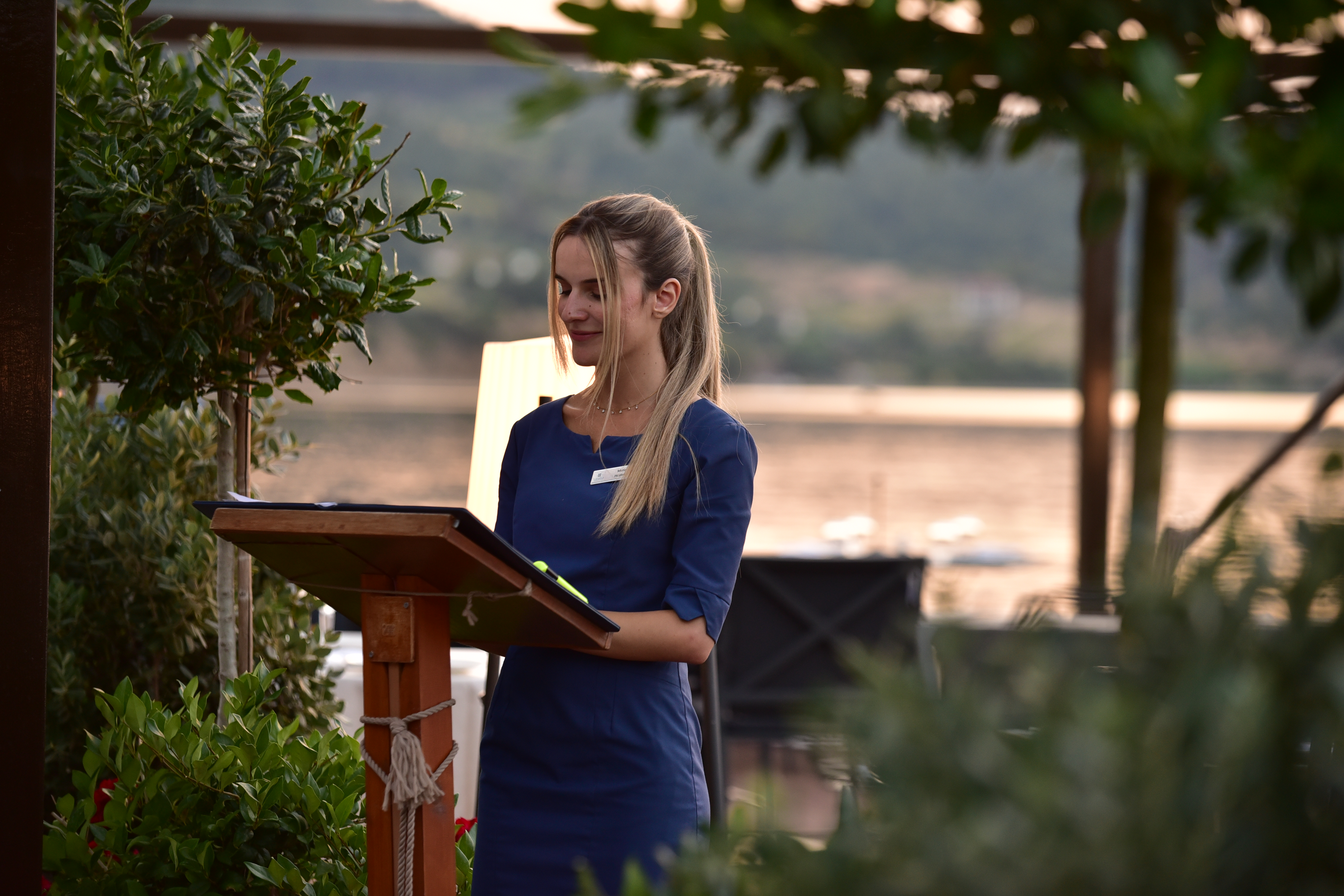 Elegant hostess welcoming guests at the seaside restaurant during sunset