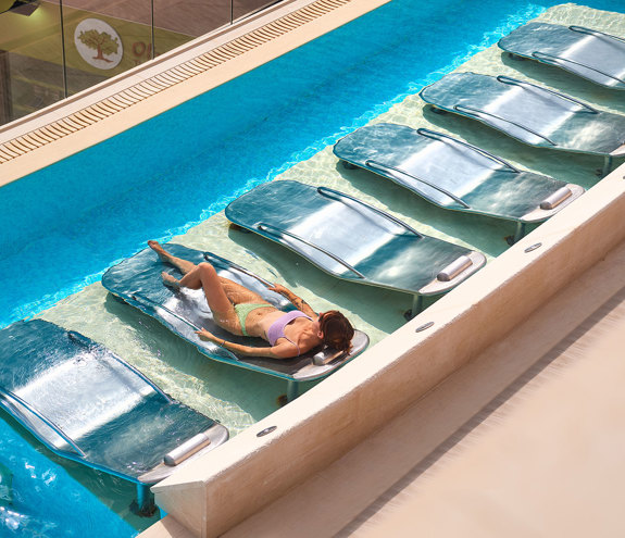 Aerial view of guest relaxing on a thermal bed in the outdoor spa pool