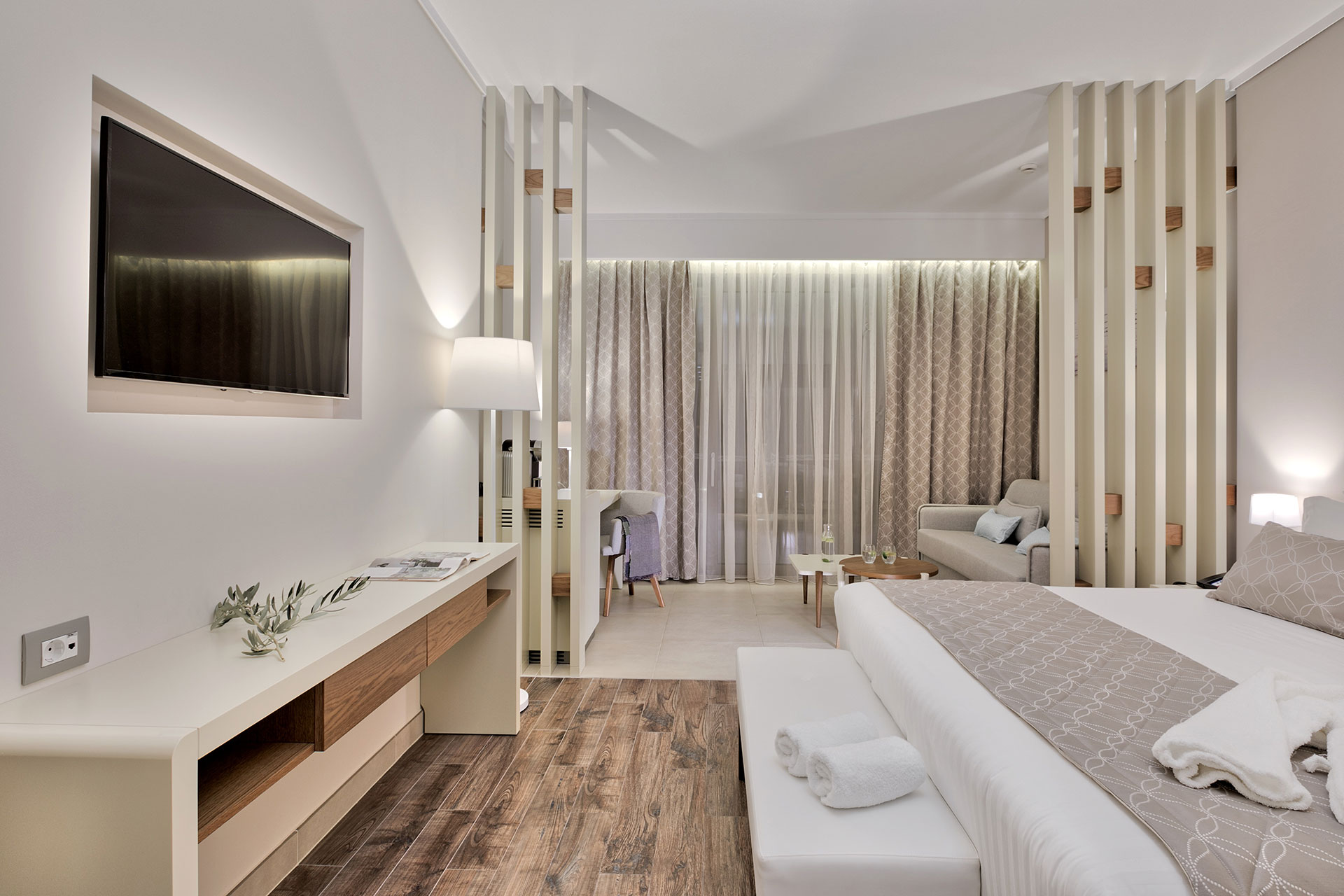 Family garden room with king bed, sofa area, TV, and floor-to-ceiling curtains overlooking the garden