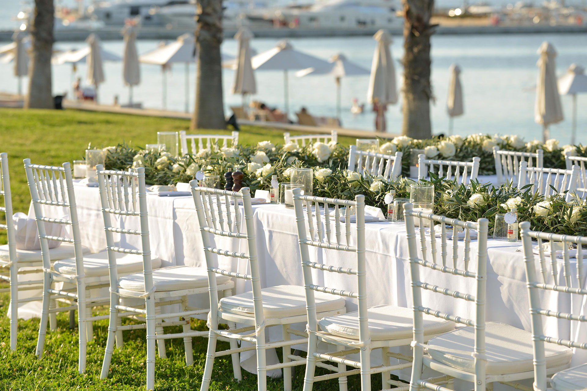 White wedding dinner tables with floral decorations by the sea