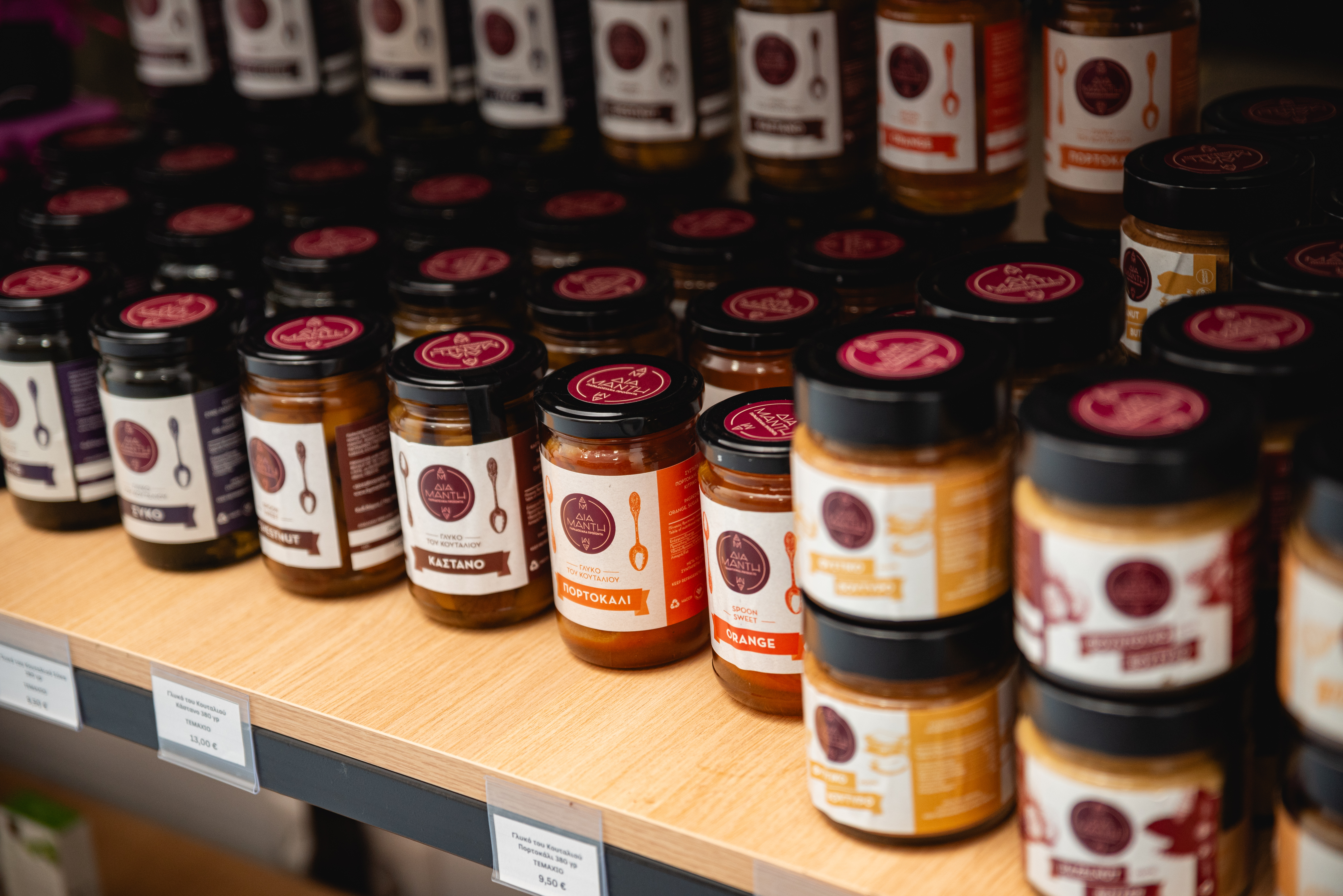 Close up of traditional Greek spoon sweets and jams in glass jars, neatly arranged on a wooden shelf