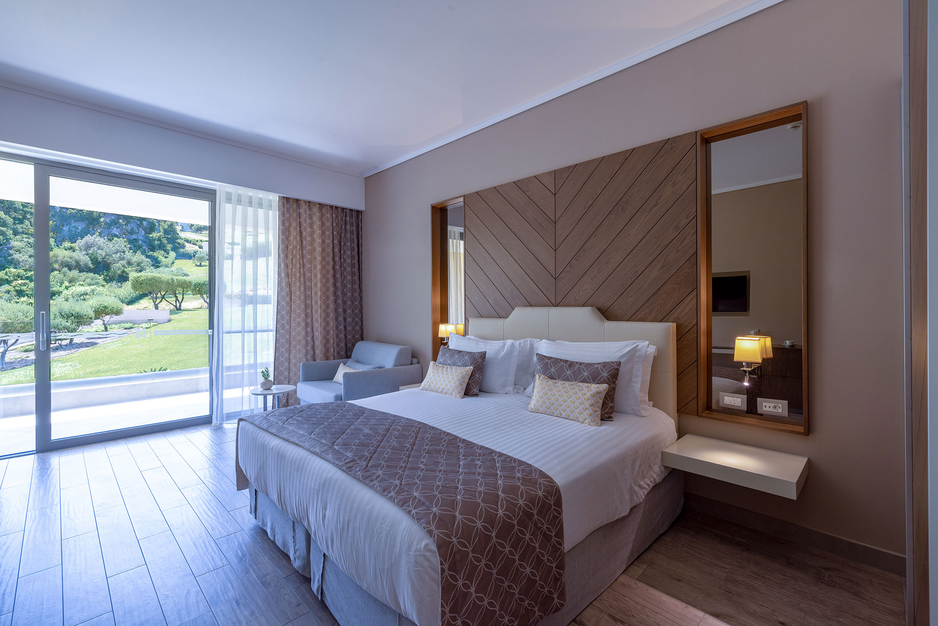 Spacious superior room with king bed, soft tones and terrace overlooking green landscape