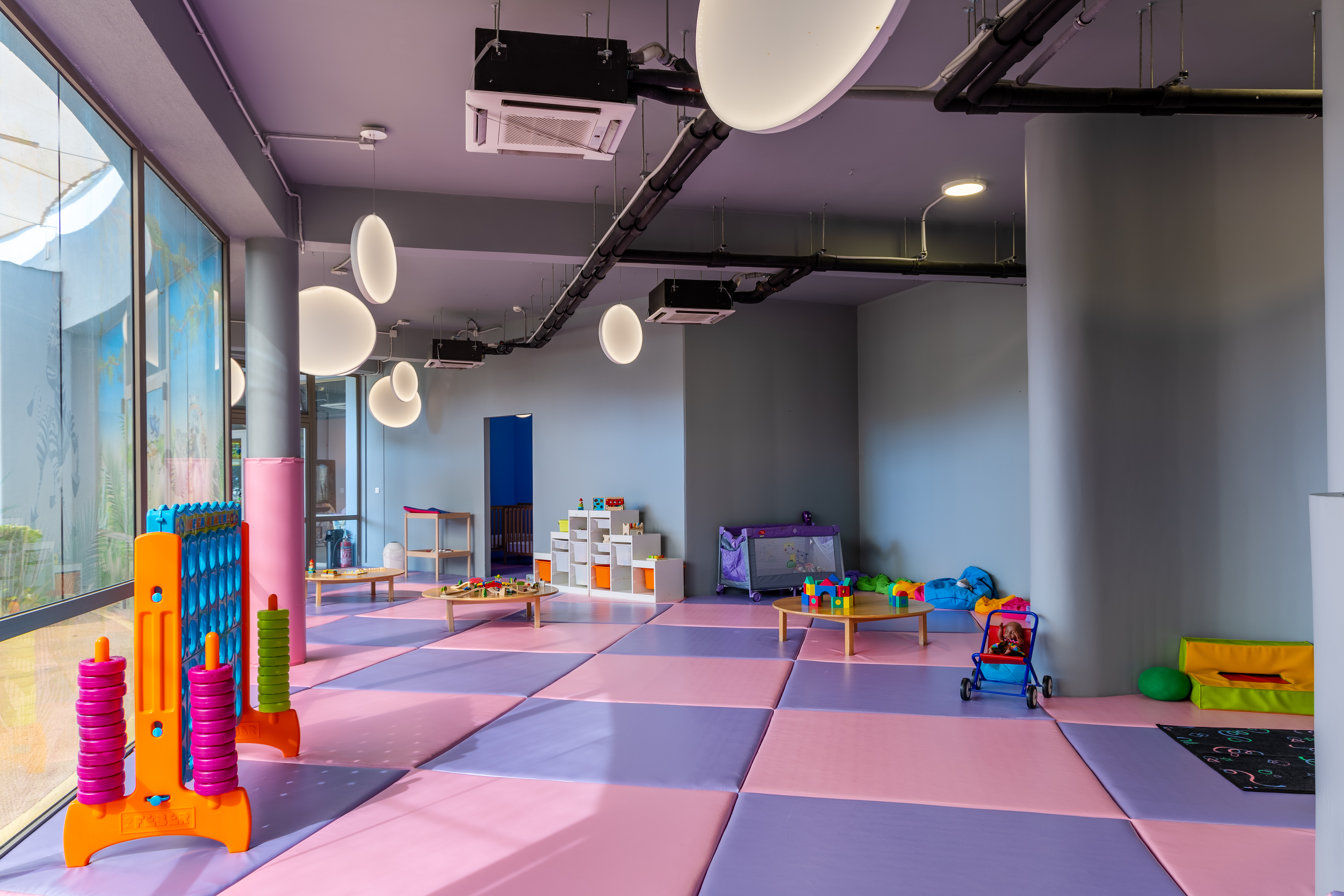Spacious indoor kids' area with soft mats, educational toys, and play tables at Kids Planet