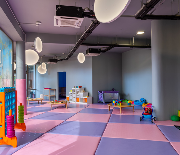 Spacious indoor kids' area with soft mats, educational toys, and play tables at Kids Planet