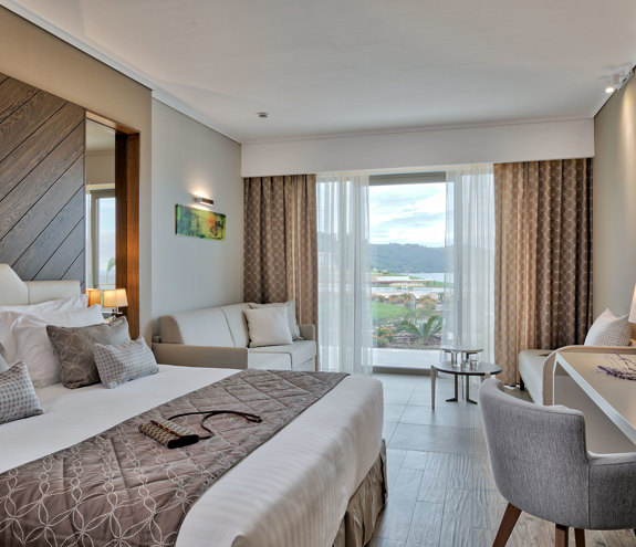 Spacious deluxe room with king bed, elegant decor and terrace overlooking lush gardens