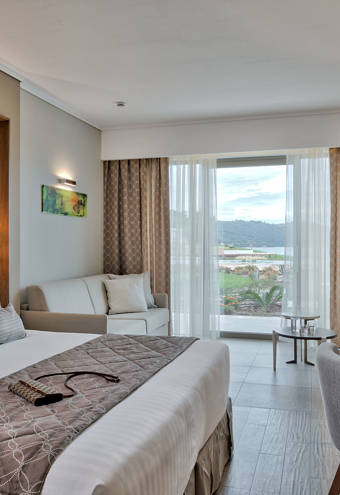 Deluxe Garden View Room bed, sofa, chair and amenities