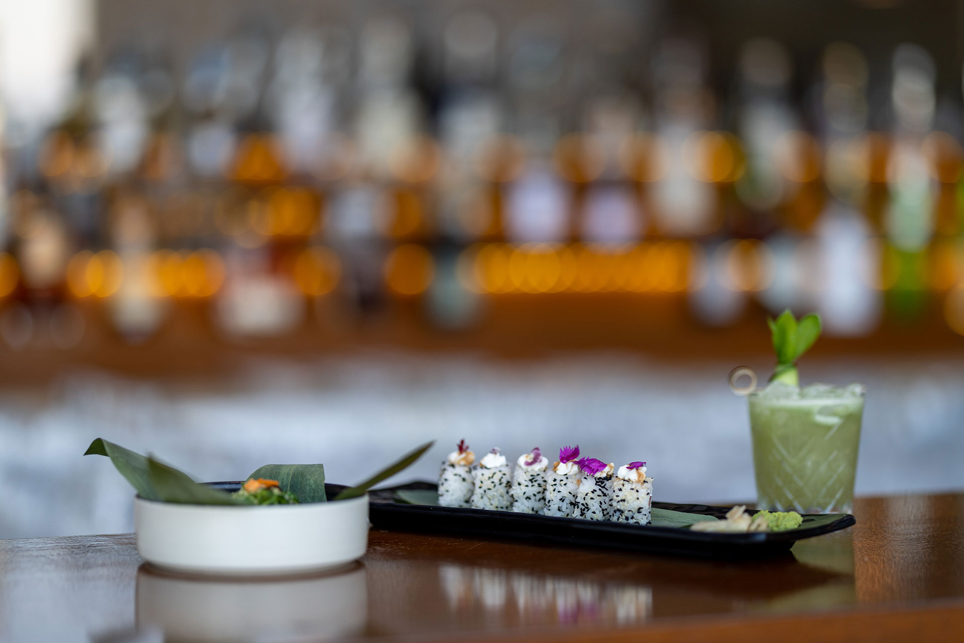 Elegant sushi platter with green cocktail and bar backdrop
